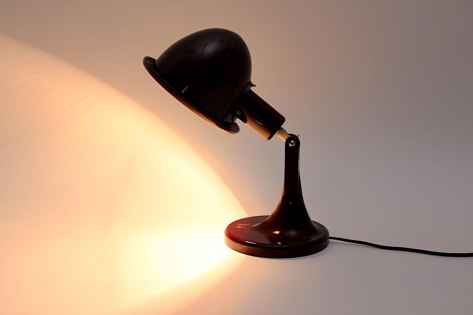 Art Deco vintage table lamp or desk lamp from bakelite in red color 1920s Germany.
Wonderful dark red vintage bakelite desk lamp, which features an oval like lamp shade. 
The oval like lamp shade is adjustable from up to down with a screwed metal