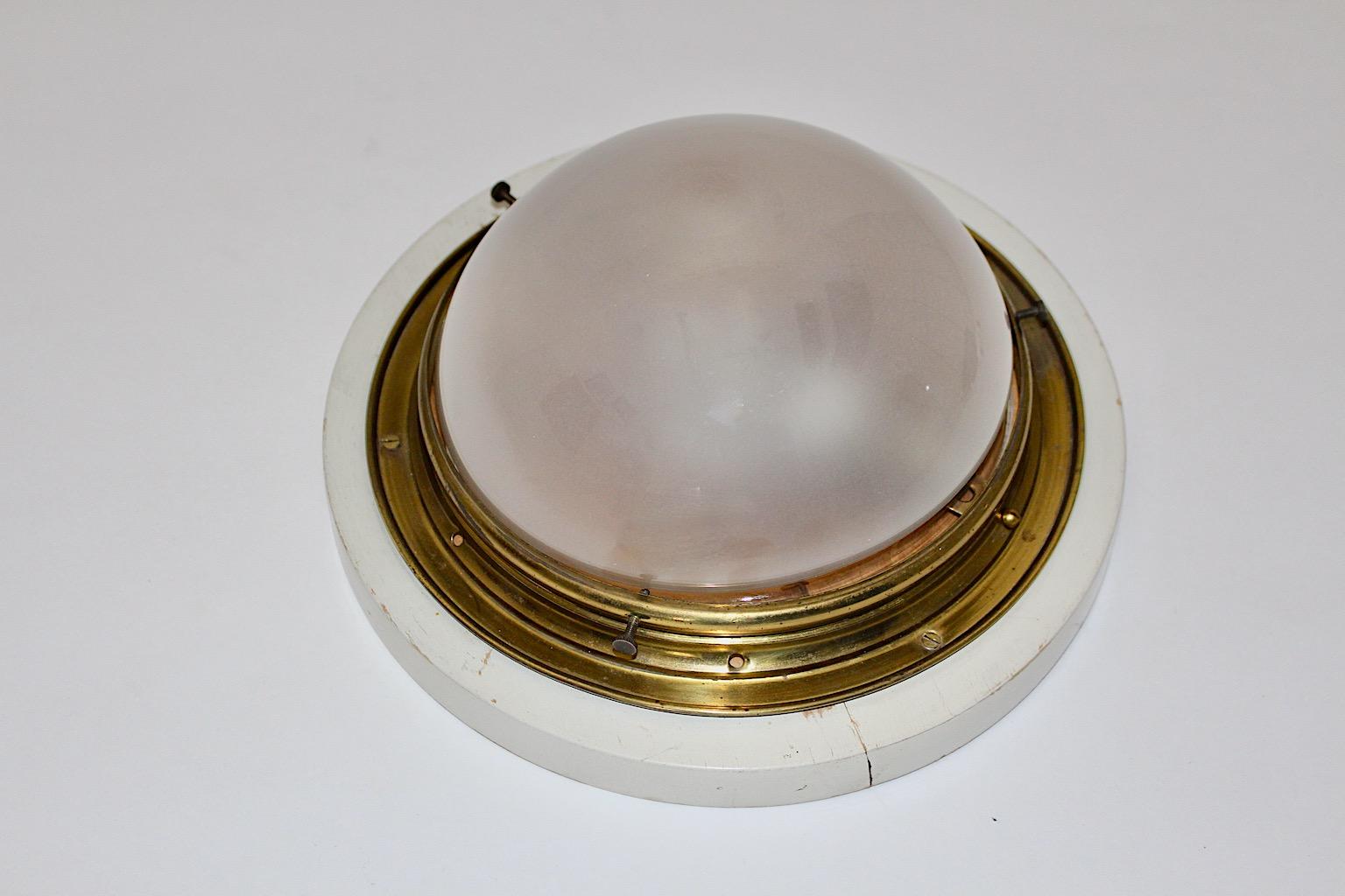 Art Deco vintage flush mount round like from brass and opaline glass 1920s Austria.
The wonderful flush mount shows one E 14 socket and is supported by the original white wooden plate, which was mounted at the ceiling.
The dome shaped shade from