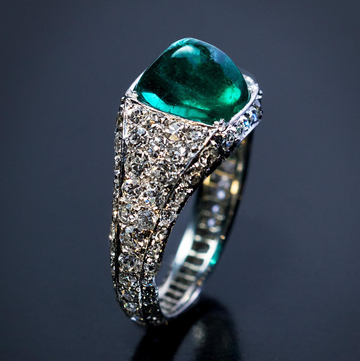 Circa 1925

This original Art Deco diamond encrusted platinum engagement ring features a pyramidal cabochon cut (sugarloaf) Colombian emerald of an excellent color and saturation.
The emerald measures 8.7 x 7.5 x 6.44 mm and is approximately 3.14