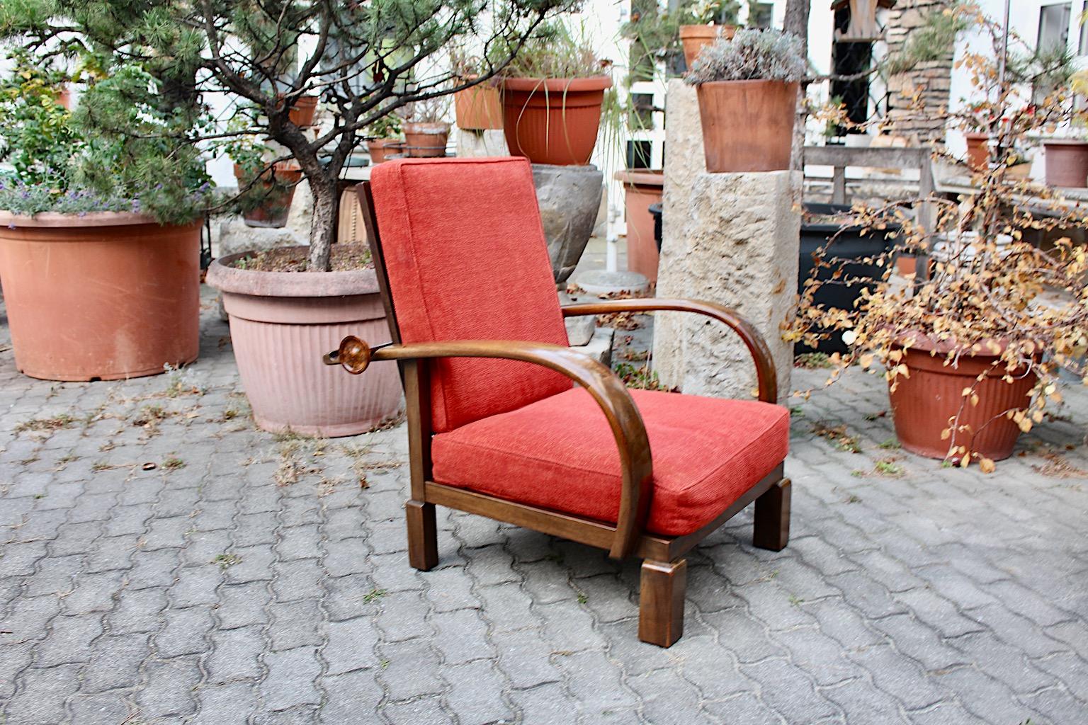 Art Deco vintage lounge chair model Kanadier from walnut with loose cushions for back and seat in coral burnt orange color, circa 1925 Austria.
While the chair frame from walnut shows smooth brown color, the upholstery features loose cushions and