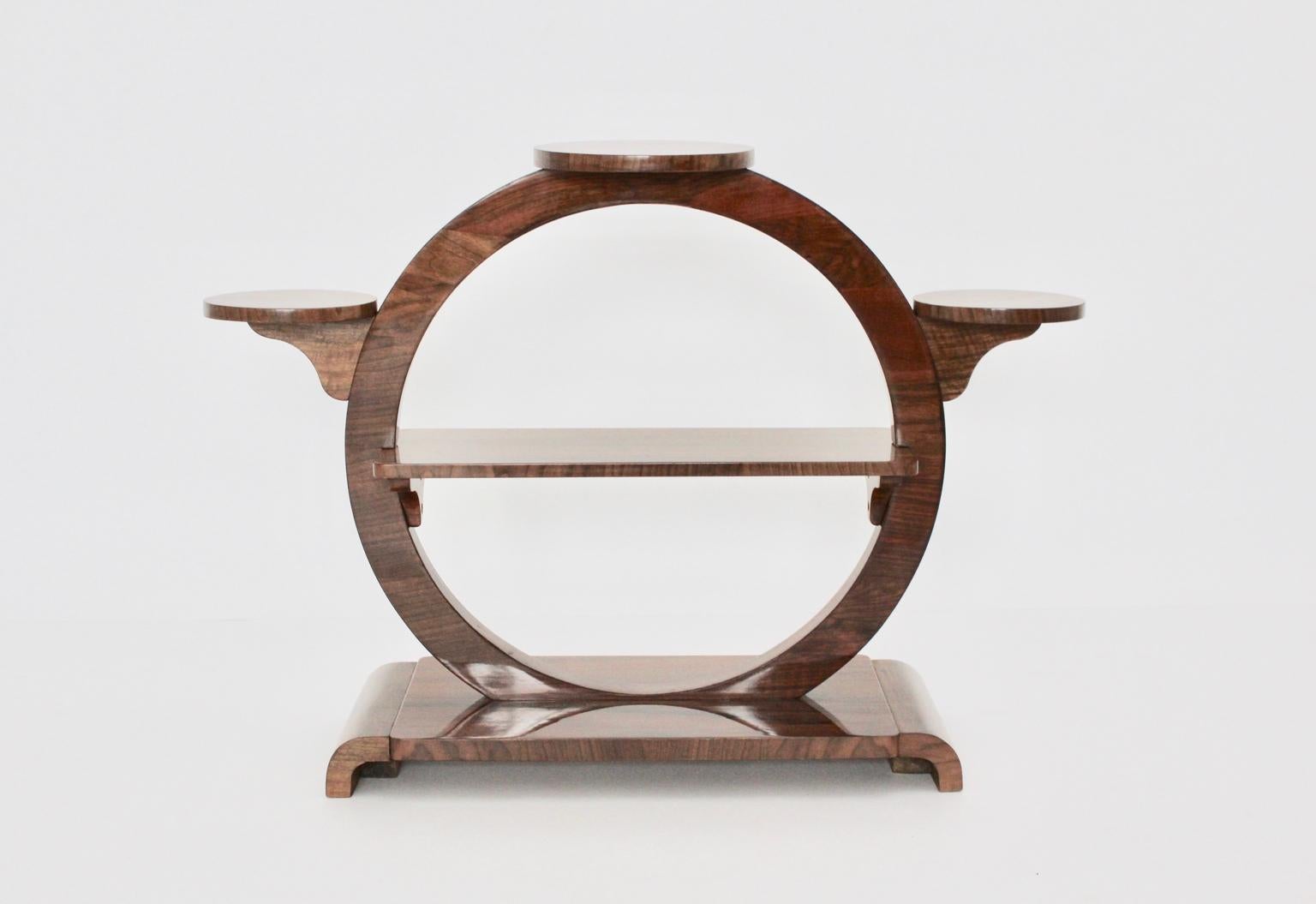 Art deco vintage walnut shelf or flower stand or room divider in brown color tone  designed and manufactured Vienna circa 1930.
An Art Deco shelf round like with 3 round solitaire plates, while a rectangular plate is located in the middle of the