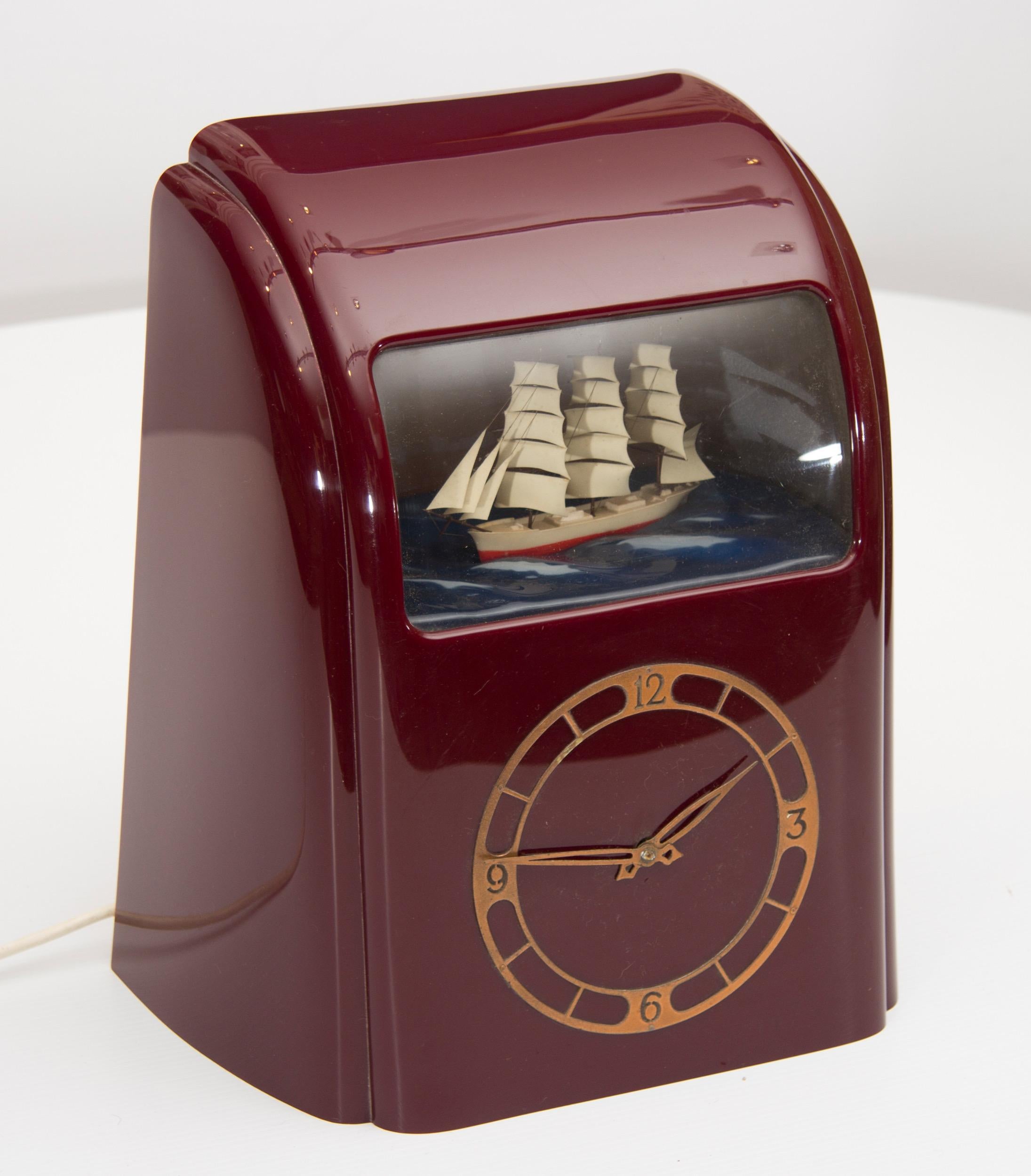 Art Deco vitascope clock in a very rare burgundy bakelite case.
Burgundy bakelite clock, the clipper boat rocks gently on the Sea while the background Illumination changes from Sunrise to Sunset, electrically operated so it keeps perfect time, with