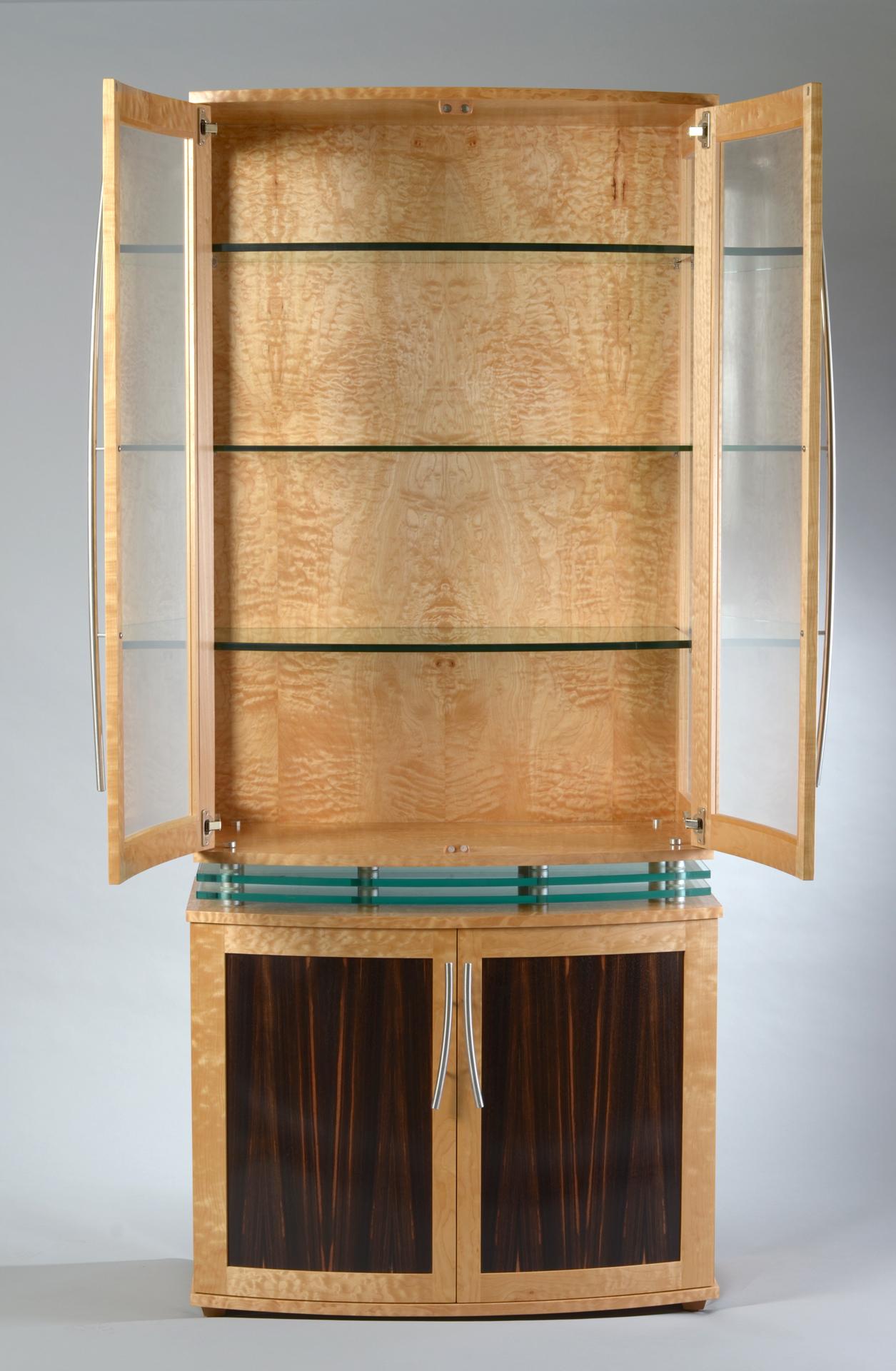 The “Levitating” Cabinet is a dramatic, art-deco style vitrine that is made by hand in Bloomington, Indiana.  Featuring a dramatic combination of the finest quilted maple and macassar ebony, every detail of this cabinet is designed and crafted to