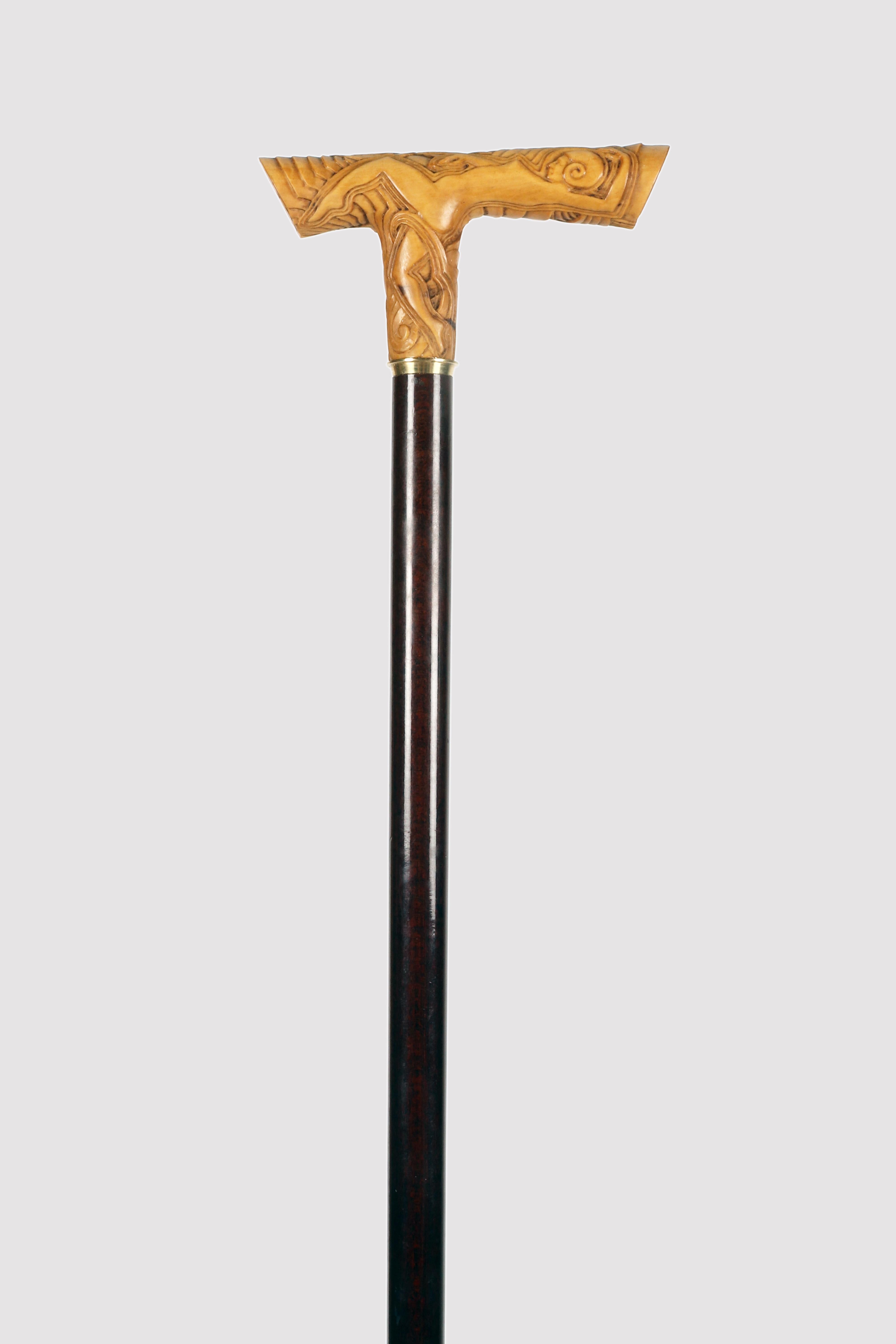 Spazierstock im Stil des Art déco. Der Knauf ist aus Buchsbaumholz, blond, fein geschnitzt und beschreibt konzentrische Bögen in verschiedenen Größen. Auf der Vorderseite des Knaufs ist zwischen den konzentrischen Kurven eine nackte Frau abgebildet,
