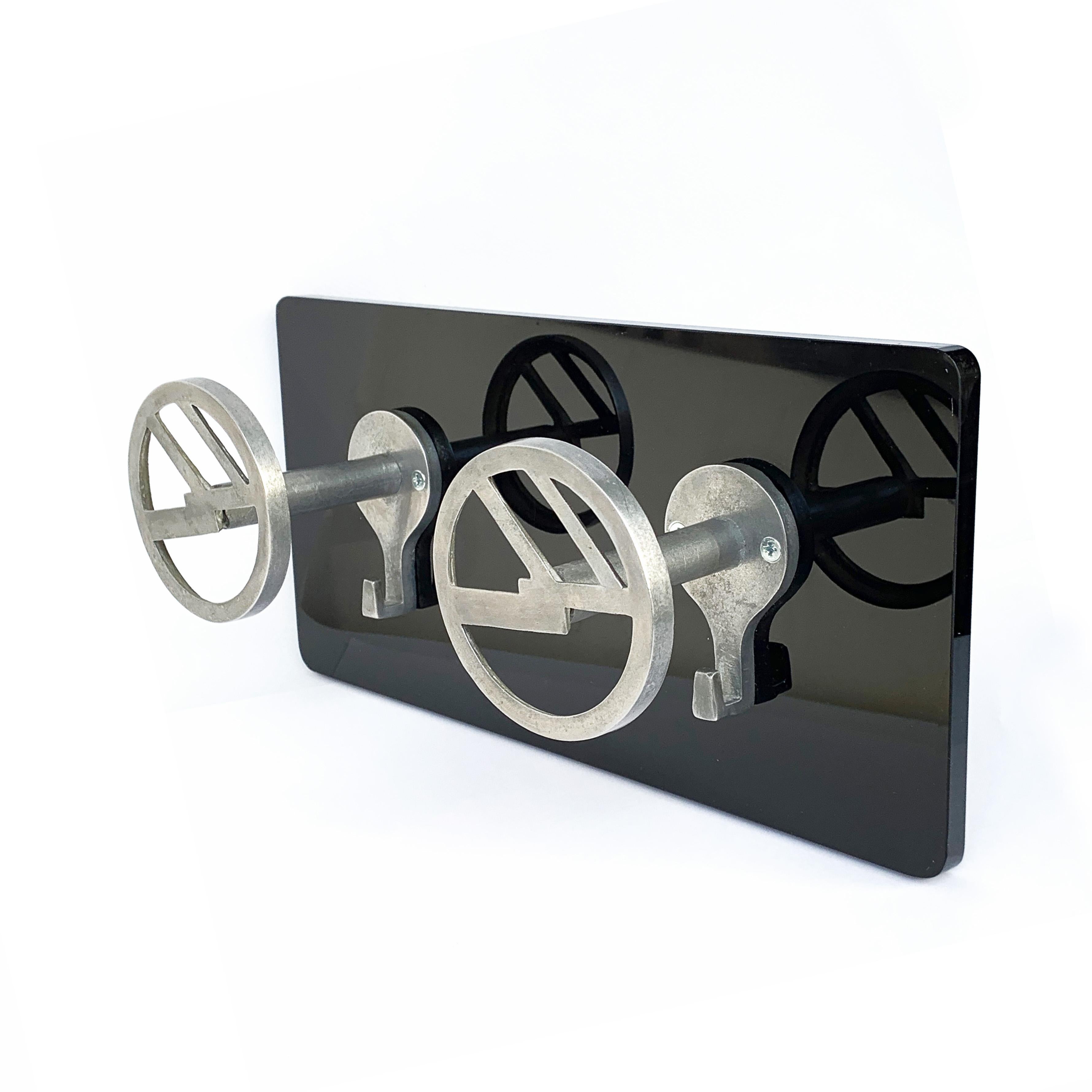 Detail of clothes hangers. The aluminium hooks are from the 1940s, mounted on a new shiny black plexiglas plate.
 