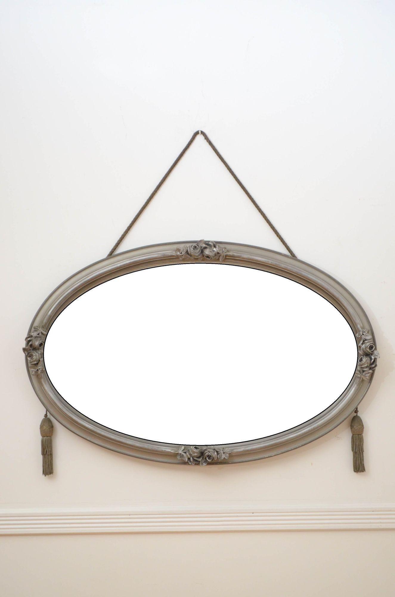 K0159 stylish Art Deco wall mirror in pewter and silver colour, having original bevelled edge glass with some foxing in moulded and flower decorated frame with original hanging rope with tassels, all in wonderful home ready condition.
