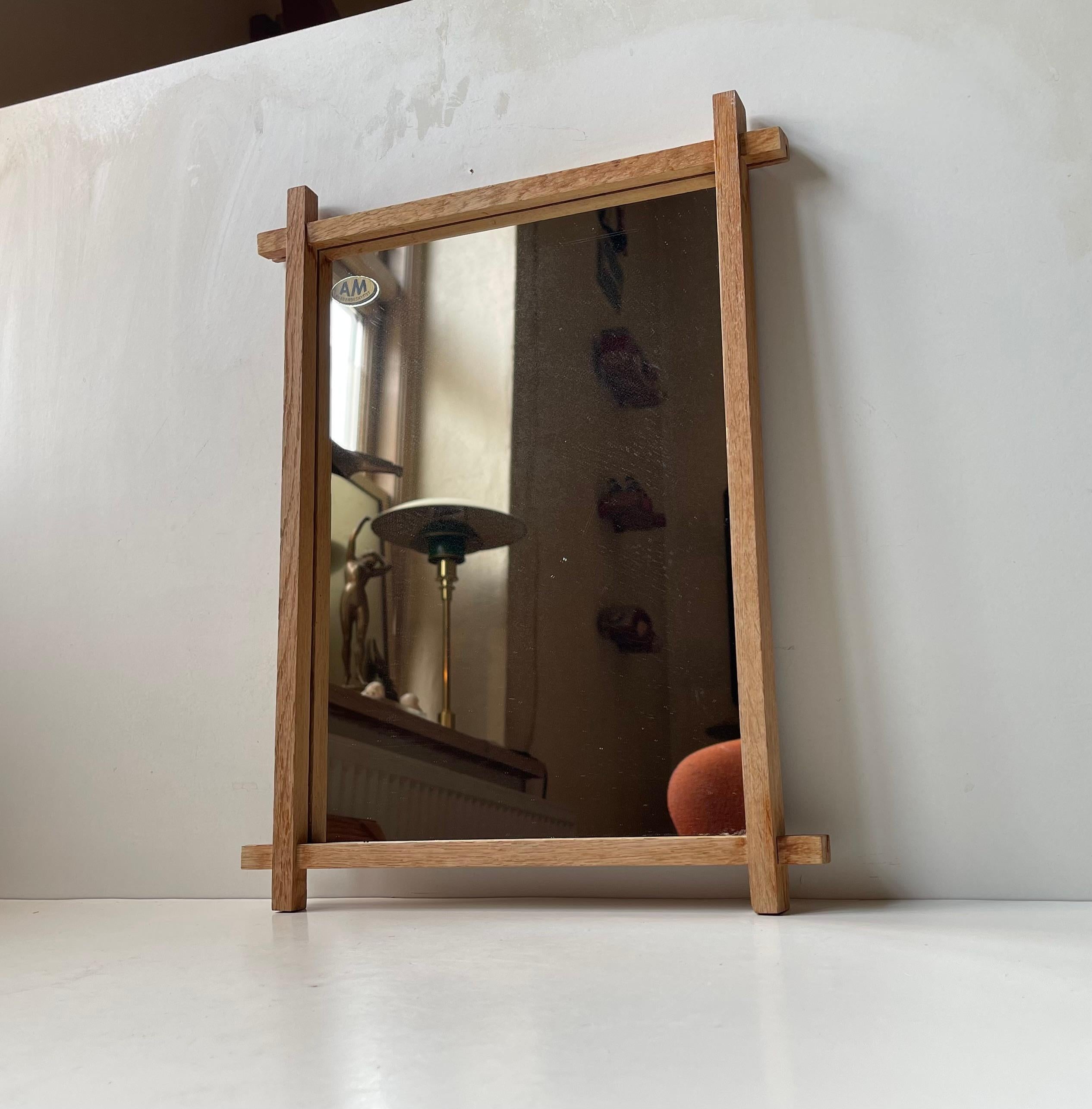 A small chain-suspended cross-bar mirror in solid oak. Made in Denmark by AM kobberbeskyttet Spejle during the 1940s. Design patented design. Suitable for Brutalist or Neo-Gothic interiors. In the style of Sven Larsson.   

Measurements: 40x30x2,5