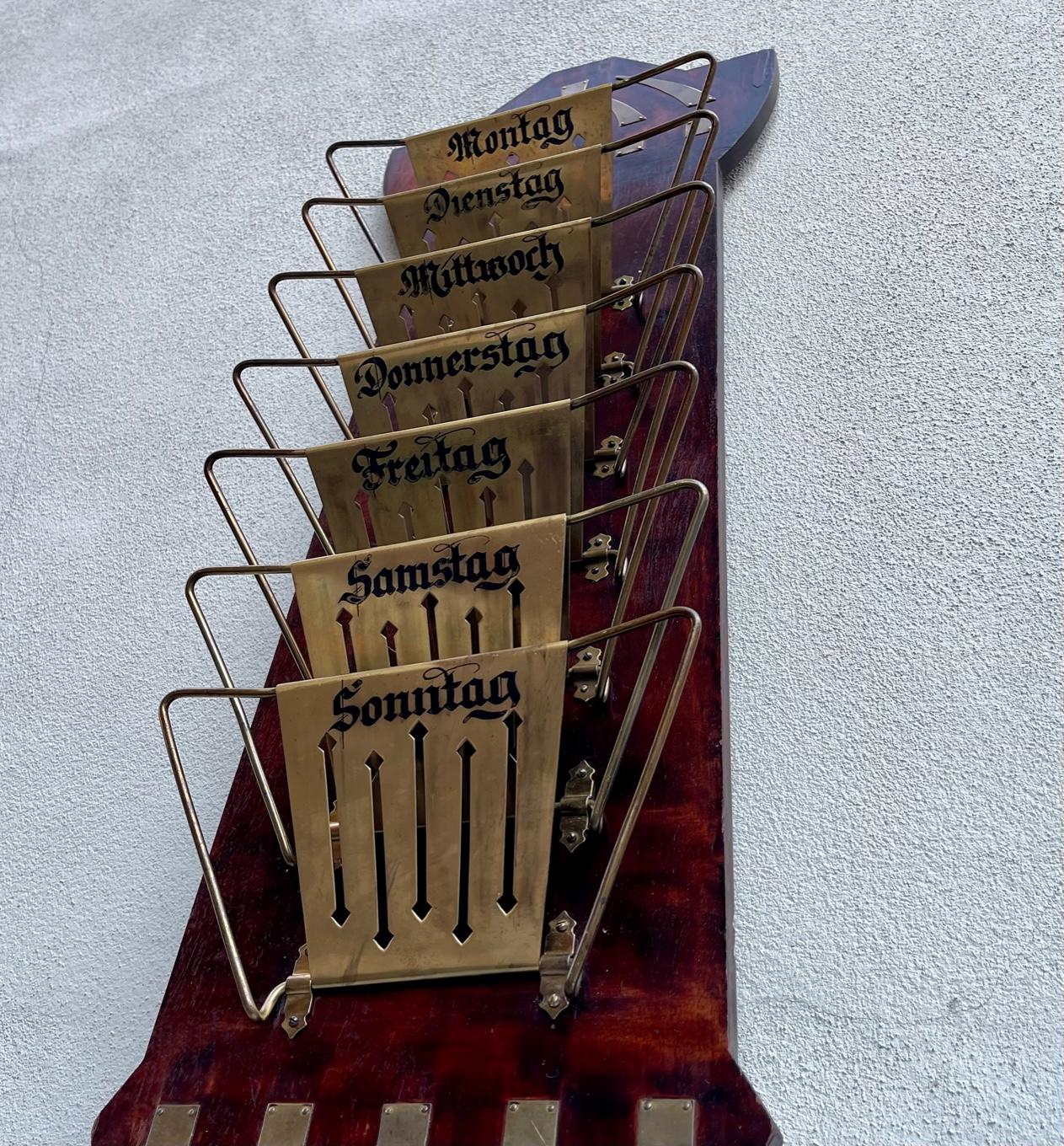 A 1920s wall hung magazine rack with 7 sleves: Montag-Sonntag (Monday-Sunday). It made from mahogany veneered oak and the 7 foldable sleves are made from partially perforated brass.It was made in Germany circa 1920-30 and stylistically it