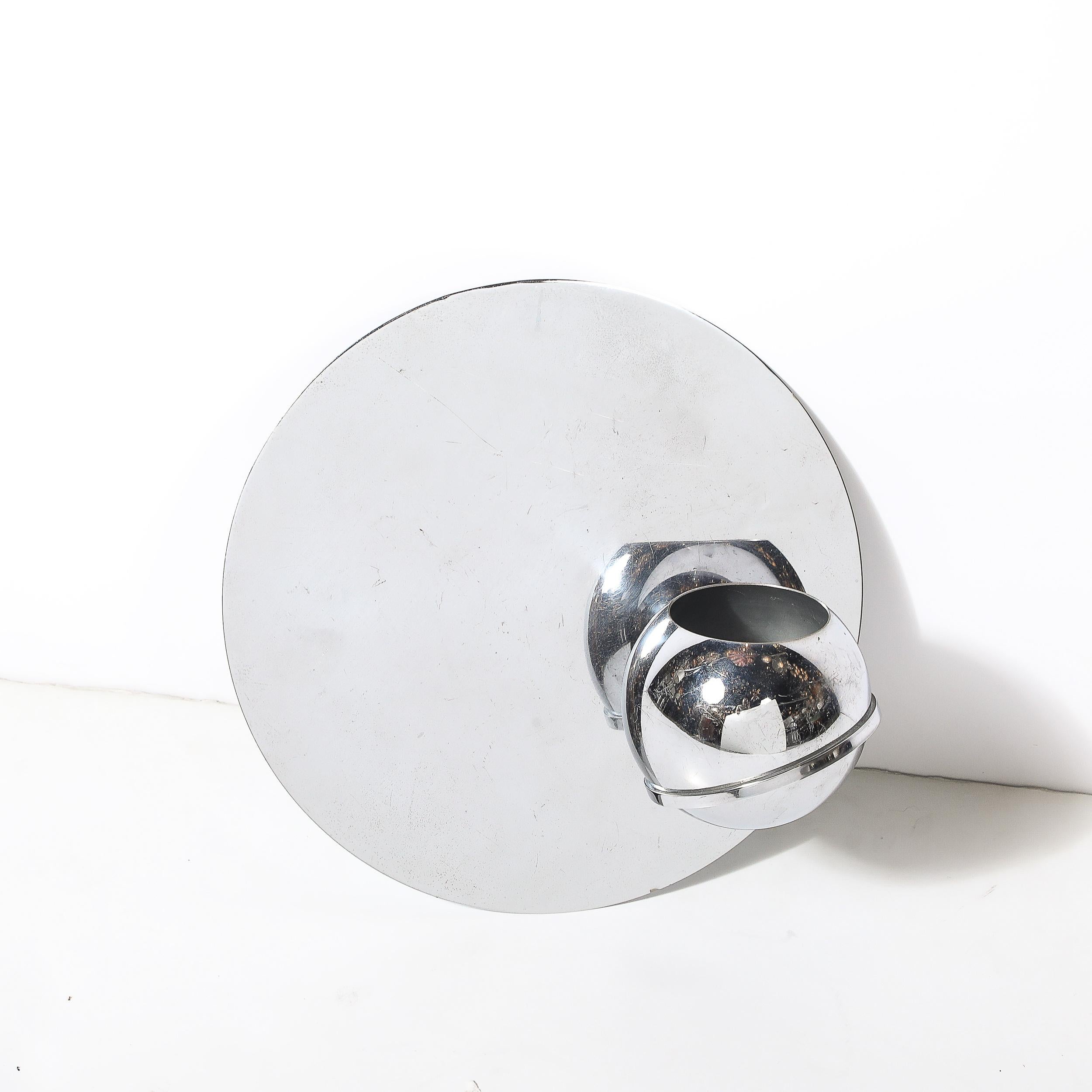 Dieser atemberaubende Art-Déco-Wandübertopf, der 1936 von Revere entworfen wurde, ist ein makelloses Beispiel für die Verbindung von Form und Funktion im modernistischen Design. Das Pflanzgefäß aus glänzend poliertem Chrom verkörpert die schlichte