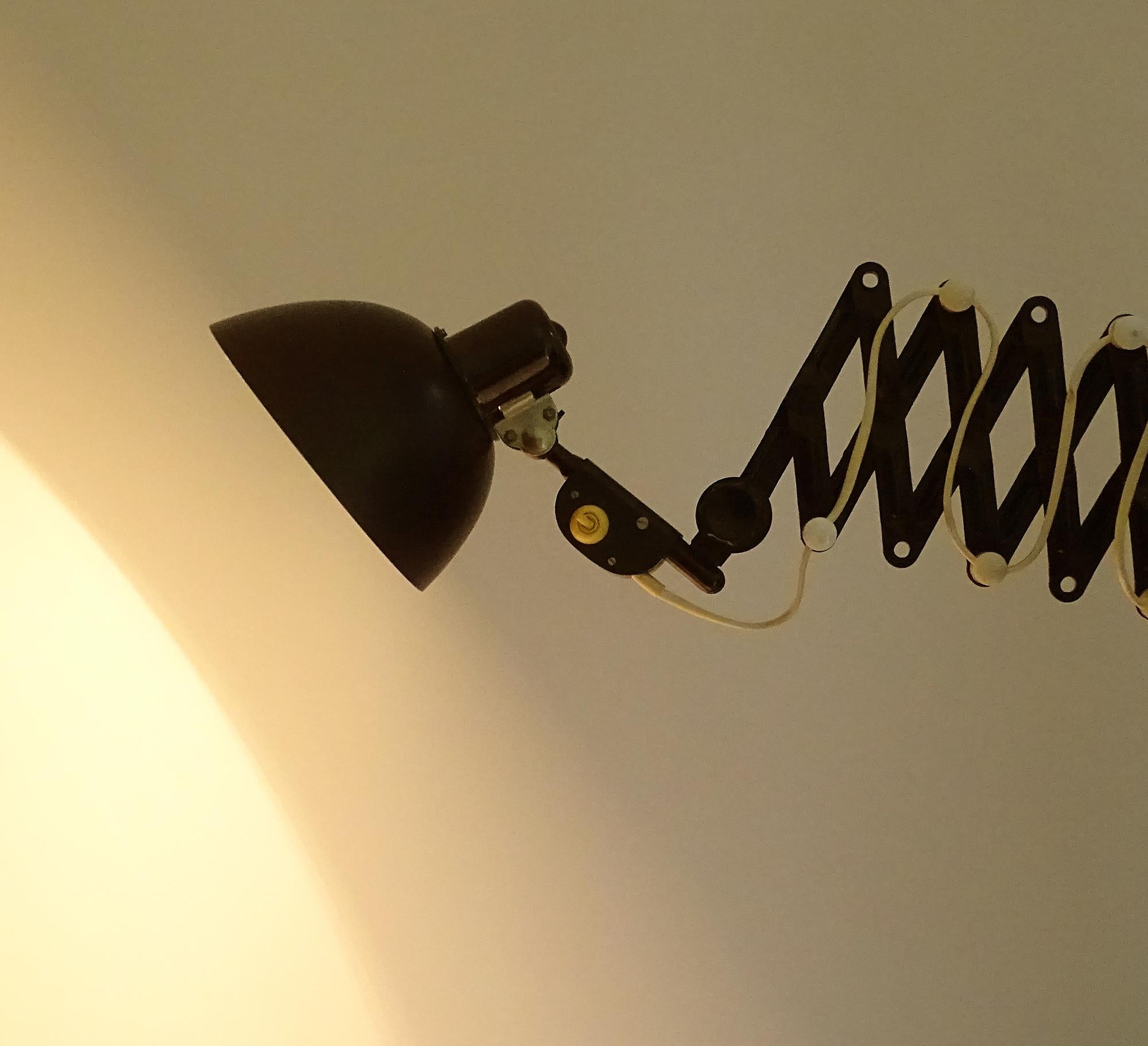 Art Deco metal and bakelite wall scissor lamp in black and white trim. Based on a design by Christian Dell. 
Wiring: The lamps have been tested with US American light bulbs under 120v and they work flawlessly.  
Dimensions (max extension):
H 8.26