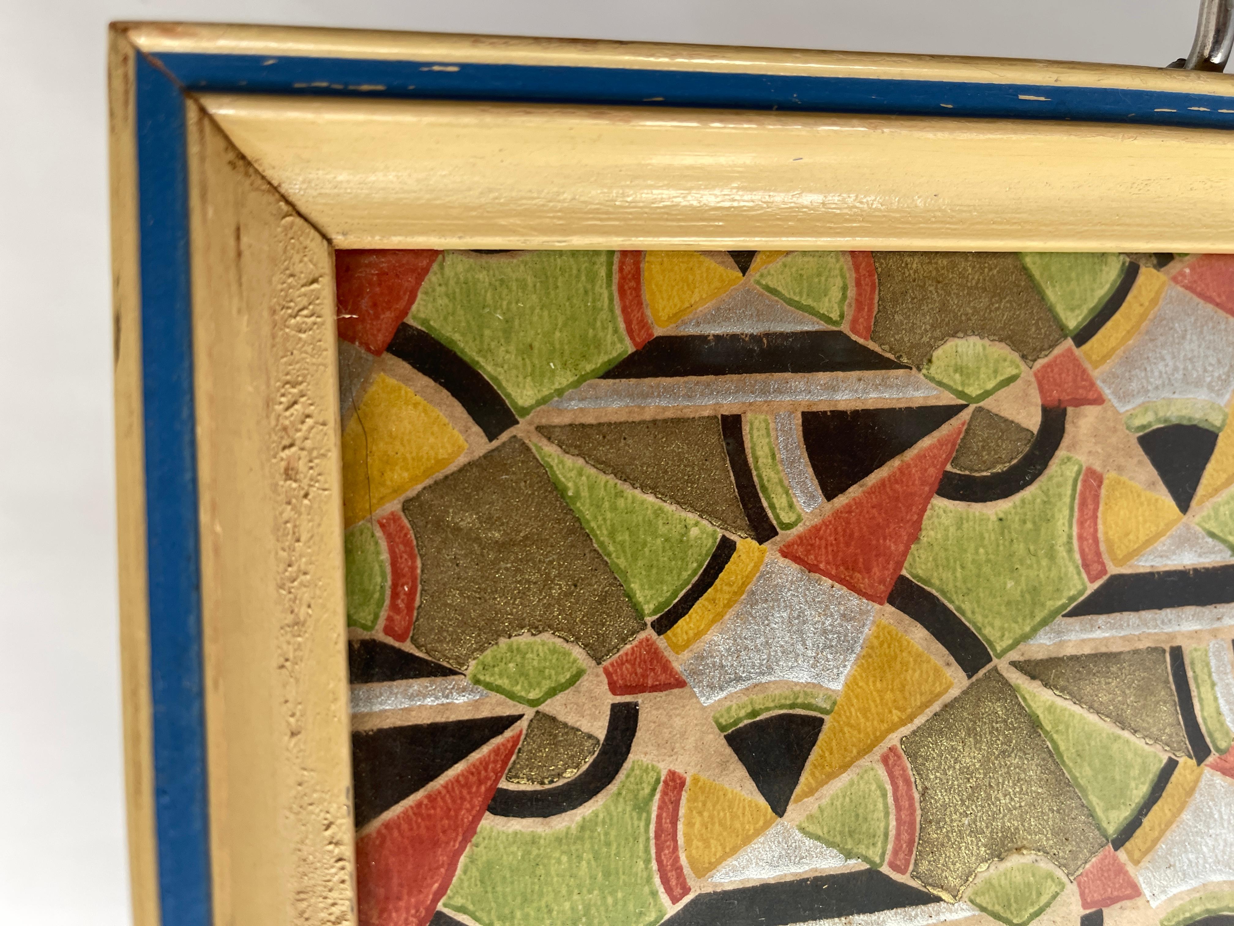 Art Deco rectangular serving tray with geometric design hand painted paper framed under glass with blue and ivory painted wood frame. One wood and chrome handle on each end. Frame has some wear., as depicted in photos.
Tray without handles measures