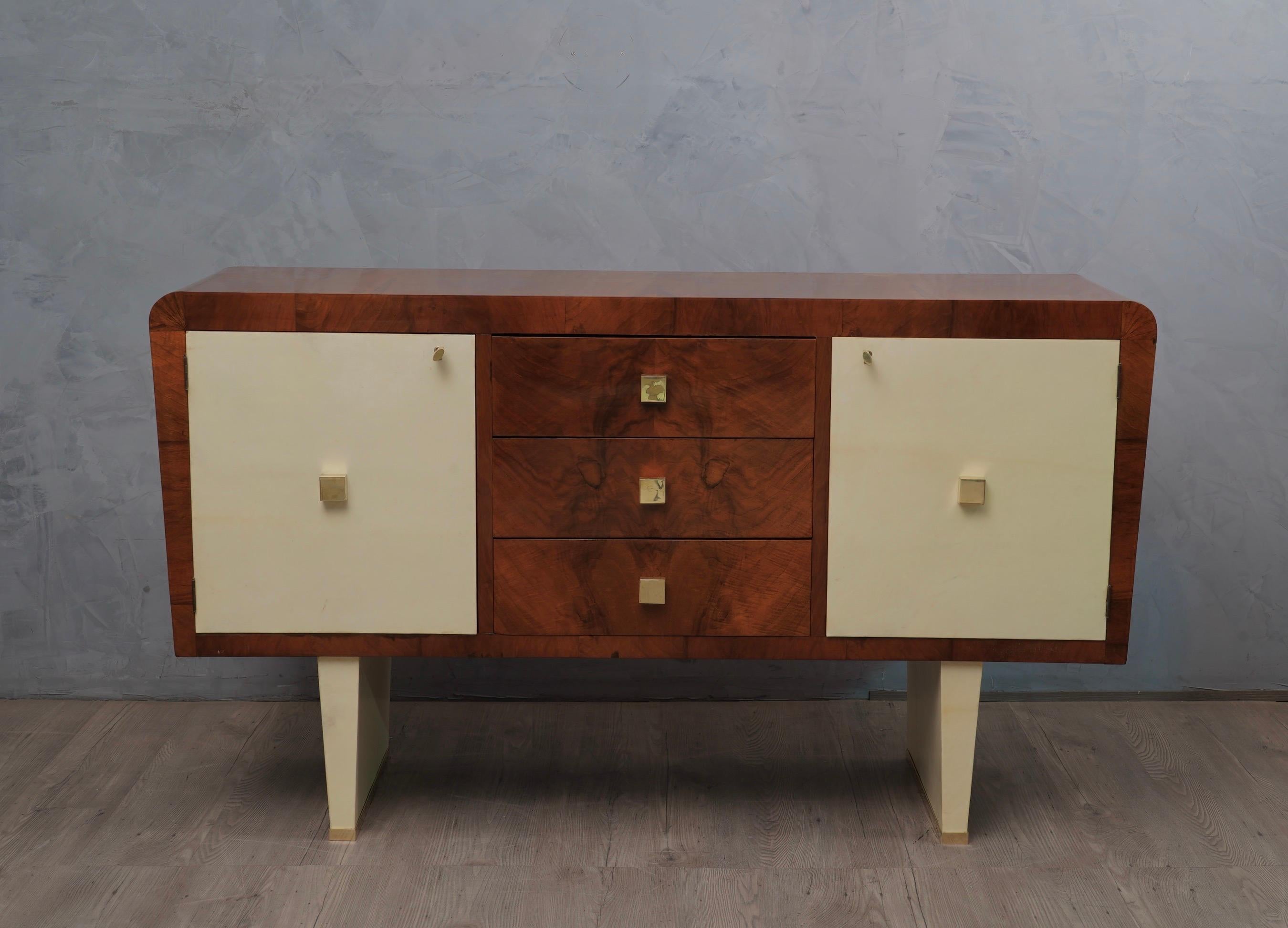 From Italian style this sideboard made of walnut wood is embellished with goatskin inserts. A subtle all over patina emphasizes the grain of the walnut.

It consists of two side doors covered in goatskin and three drawers in the middle of walnut