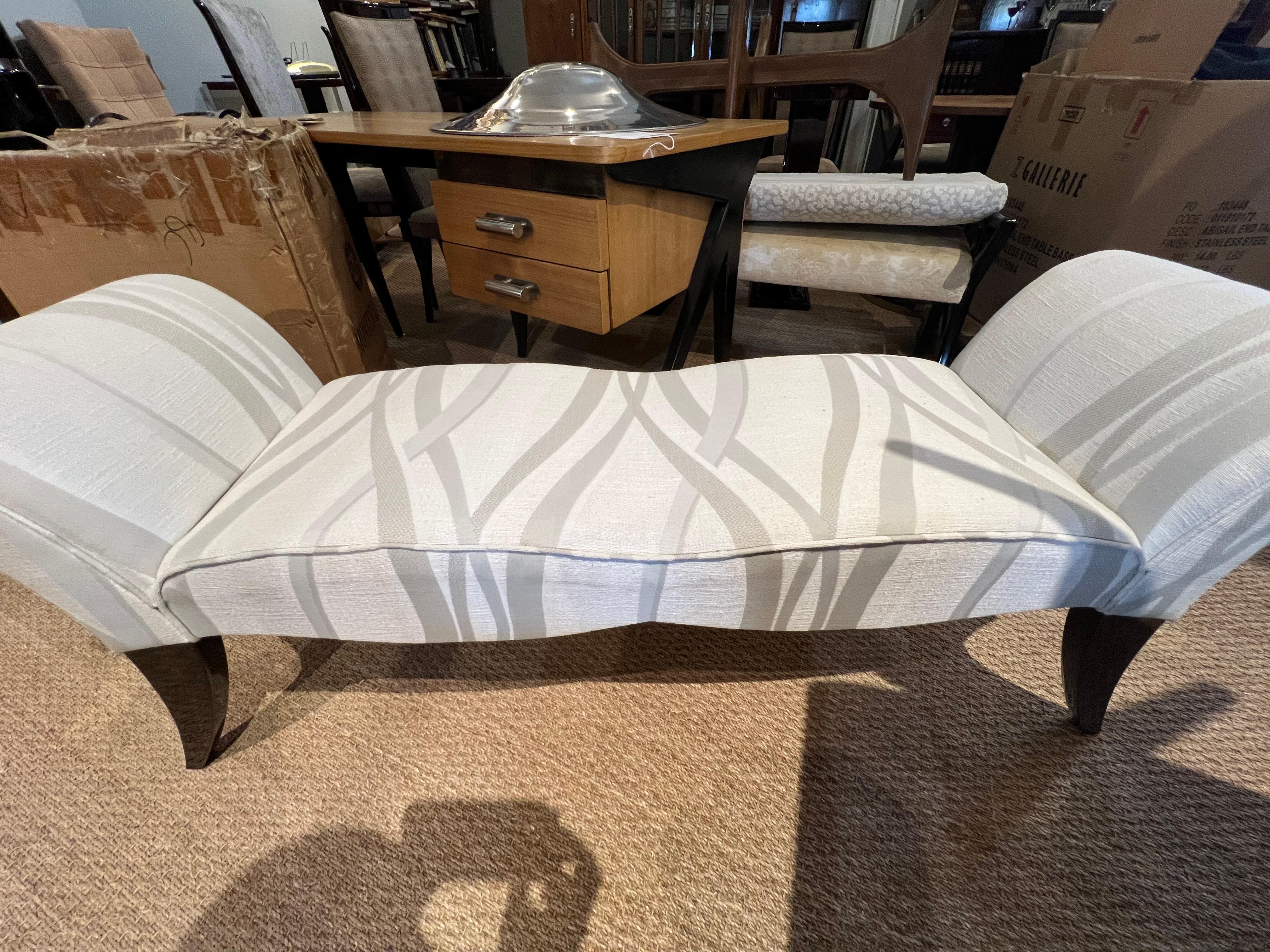 Art Deco bench is made out of walnut wood. Seat is newly re-upholstered in a light grey fabric. It supported and elevated by the 4 semi-curved legs, where 2 legs on each side are connected with each other, creating crescent shape. 
Condition is