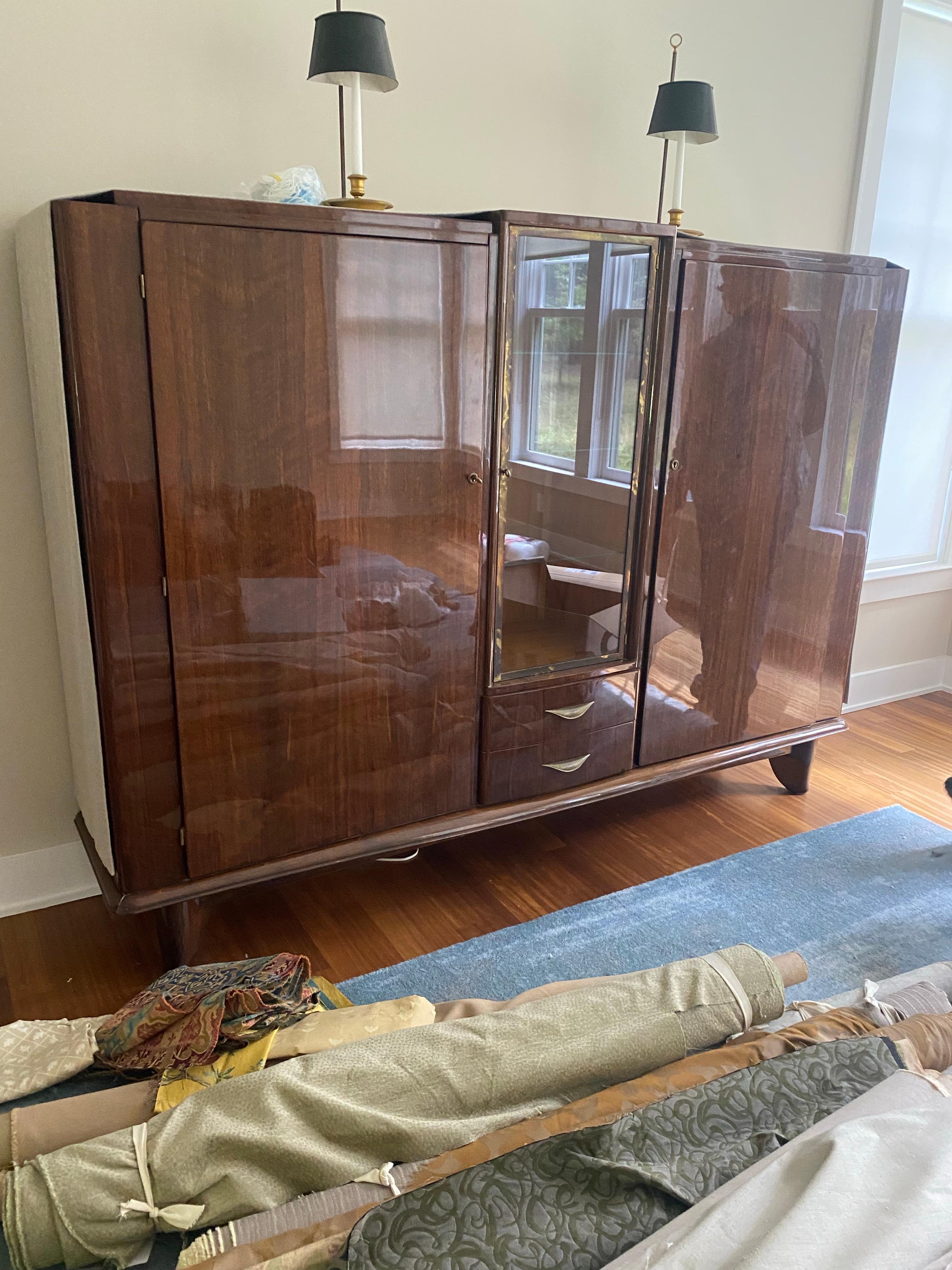 Art Deco display cabinet, 1920s.  Crafted from a richly figured wood, possibly walnut or mahogany, it features a high-gloss finish, geometric form, and streamlined design typical of the period. The cabinet boasts two large side cupboards flanking a