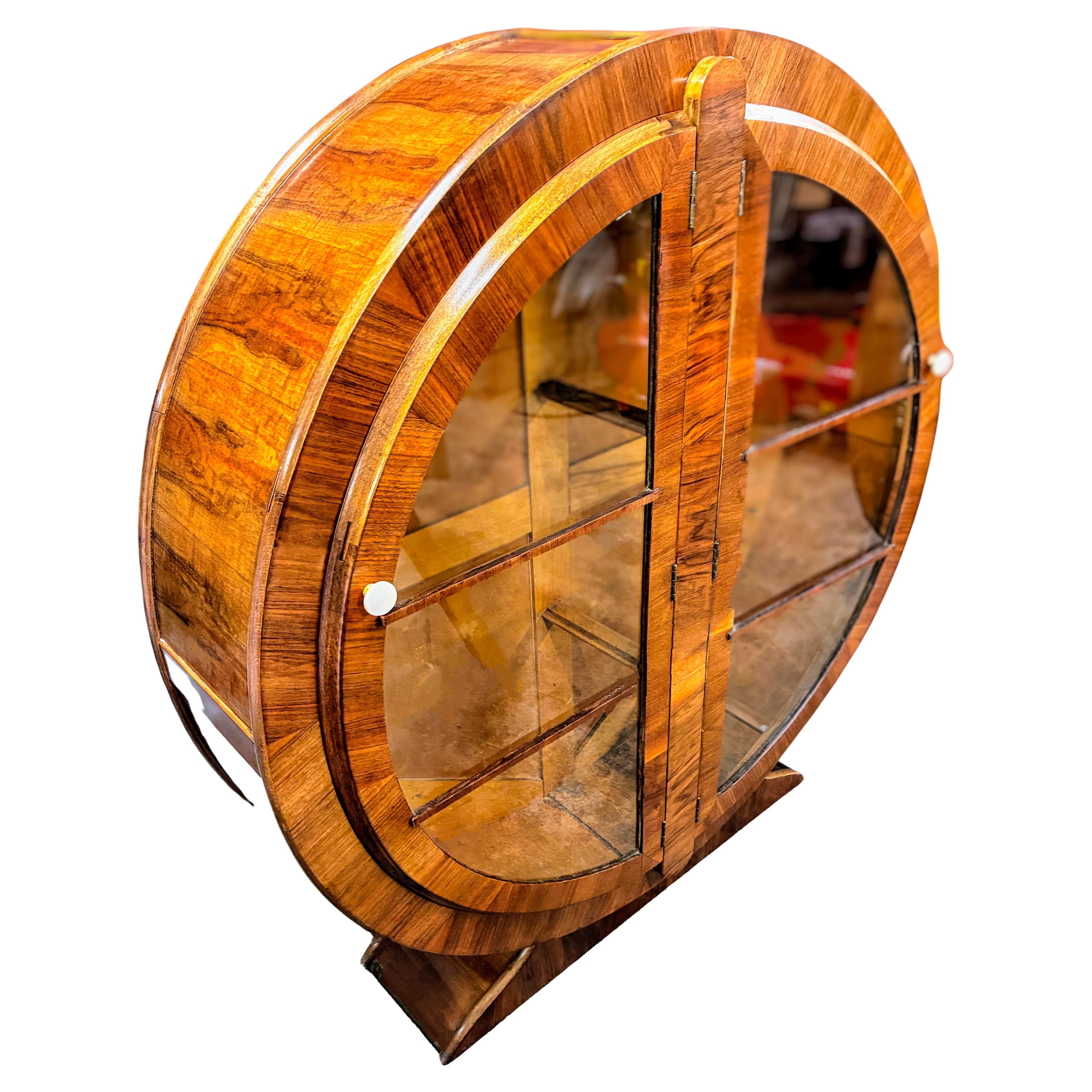 Offered for your consideration is this superbly stylish and totally original 1930s English Art Deco round display cabinet. Figured walnut veneer in a warm mid-tone coloring with a distinctive light and dark alternation running throughout and