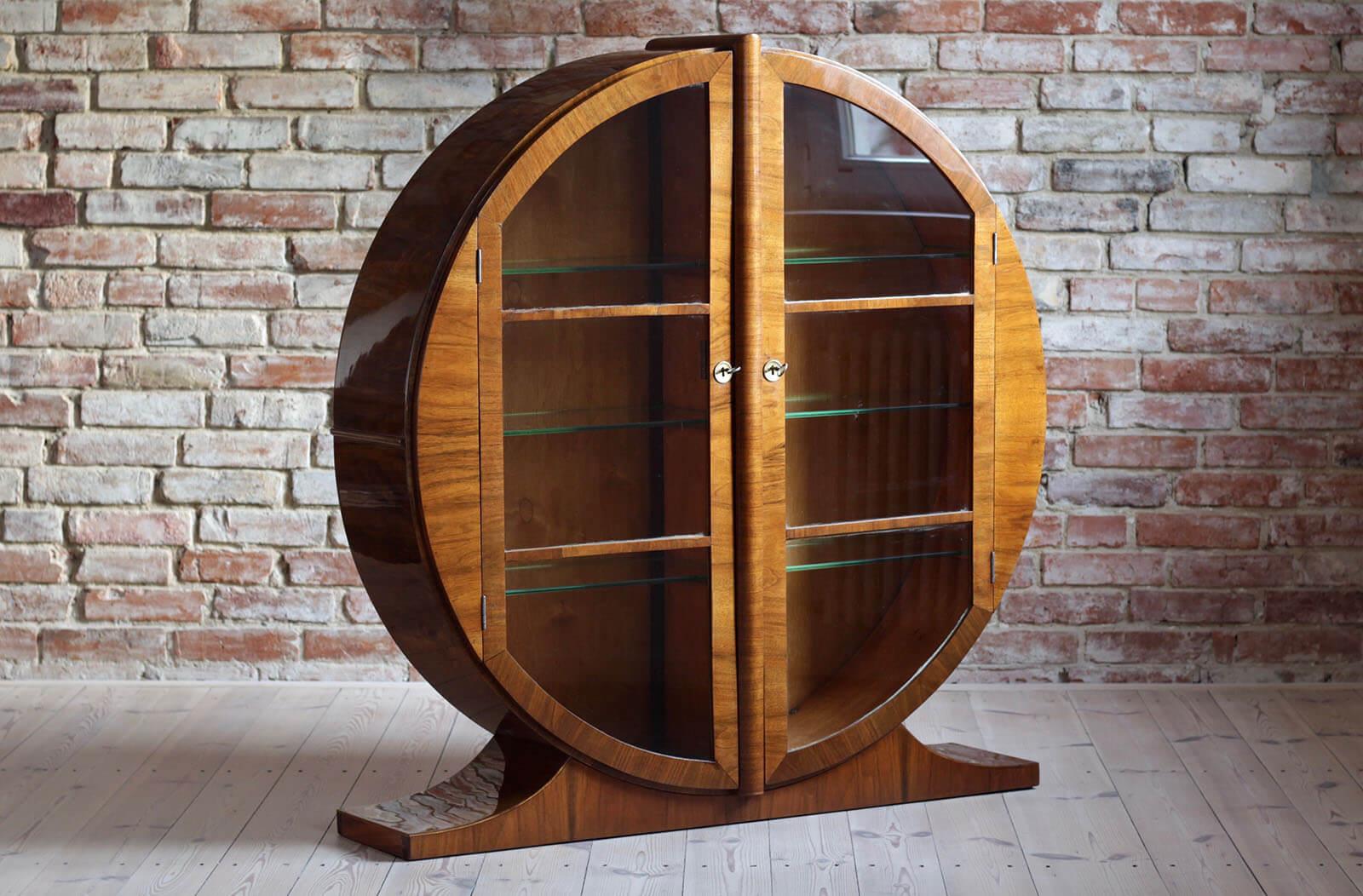 English Art Deco round display cabinet from circa 1930s-1950s. The piece is veneered with walnut veneer in a warm mid-tone coloring and features a generously sized interior display area for all your collection. On each side there are 3 glass