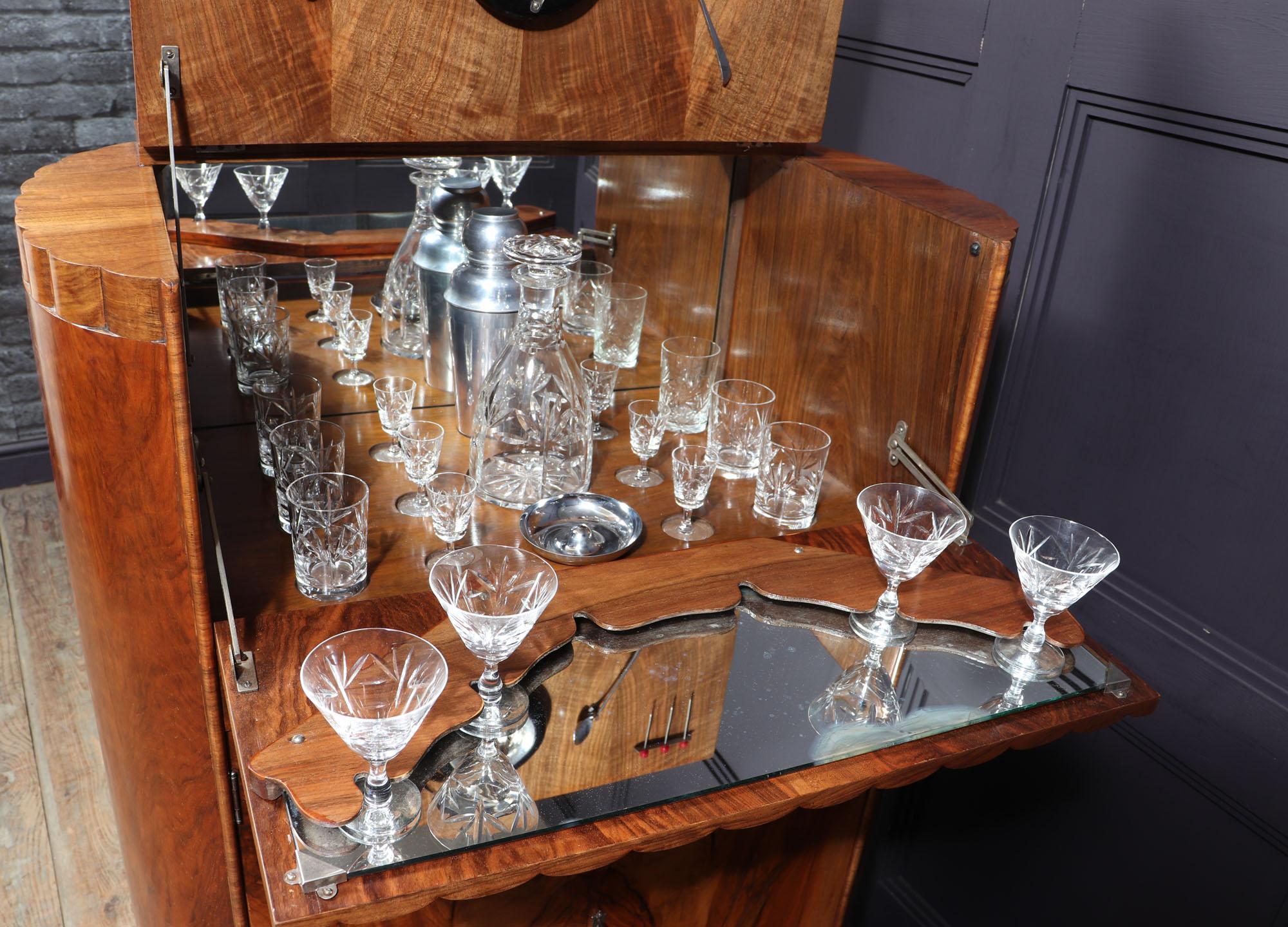 A very stylish English made cocktail cabinet with pop out mirrored top section, with interior and glasses as shown in photos. The cabinet has fluting and reeded detail all in figured walnut with very unusual and rare shaped rounded ends the lower