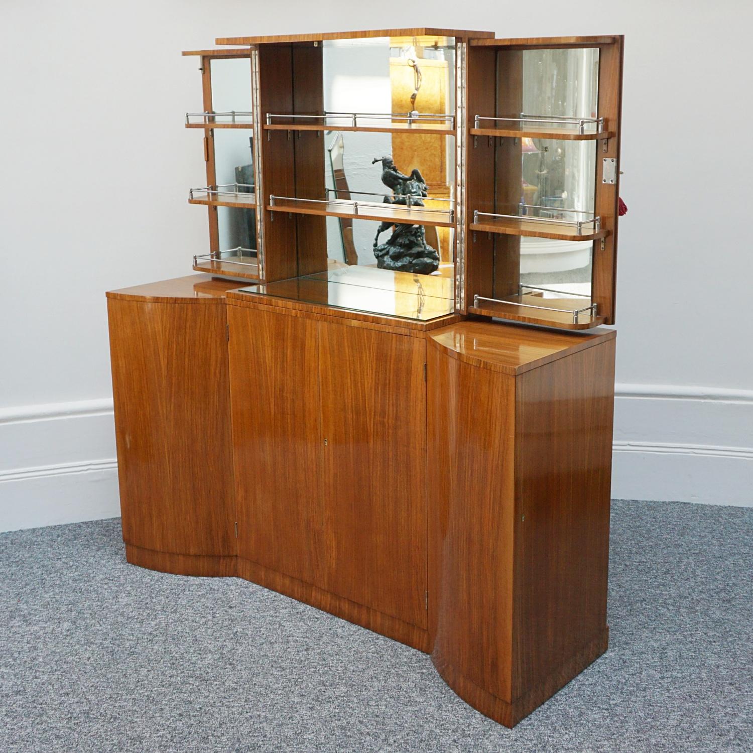 Art Deco Cocktail Cabinet. Upper section opens to reveal mirrored glass interior with chrome fittings and pull out mirrored mixing tray. The lower central section with walnut lined bottle storage, with two adjacent cupboards opening to either side