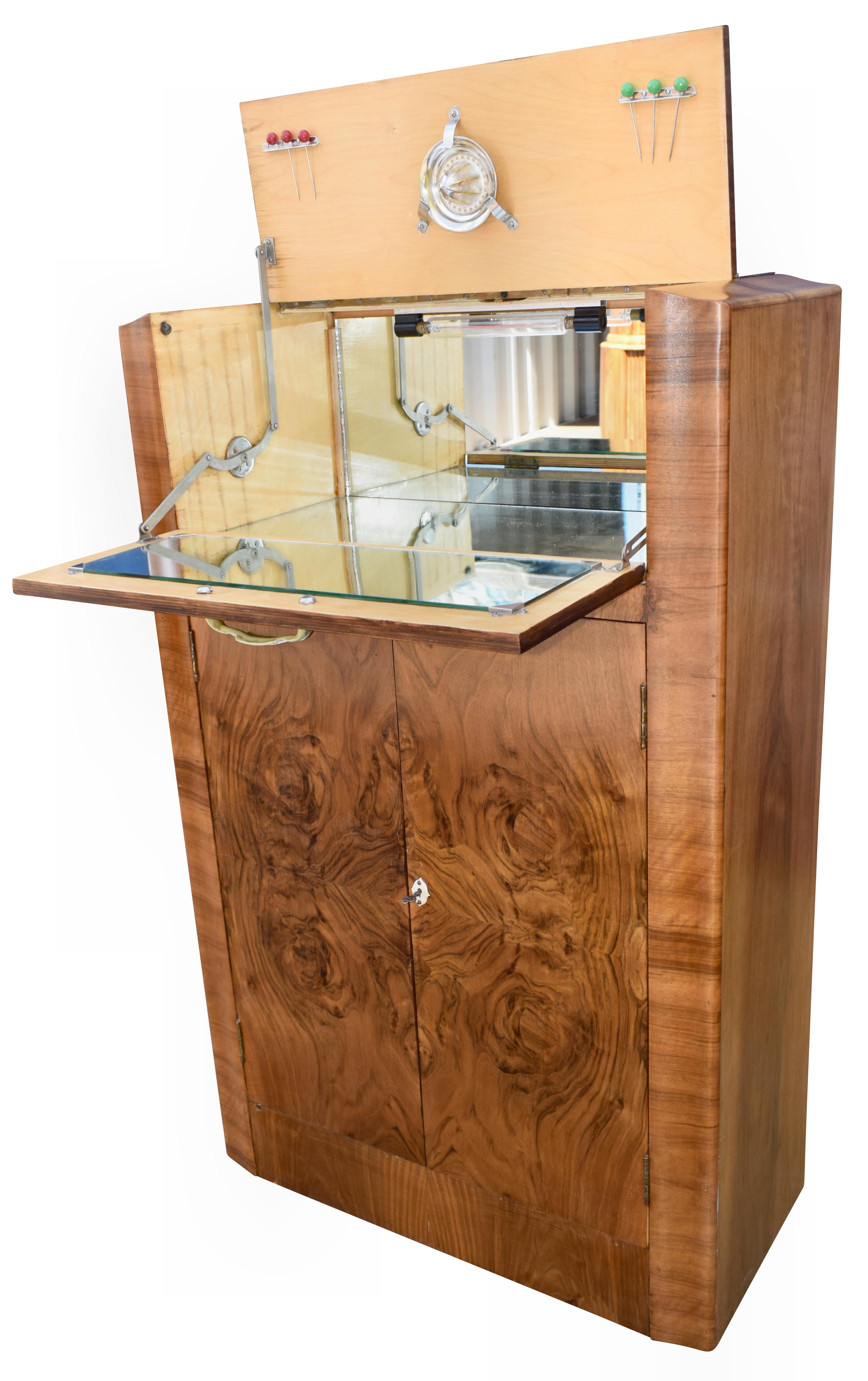 Beautiful 1930s Art Deco walnut upright cocktail cabinet, every deco interior should have one of these! Features a drop down top which reveals a mirrored interior and storage for bottles and glasses. A generously sized cupboard below offers plenty