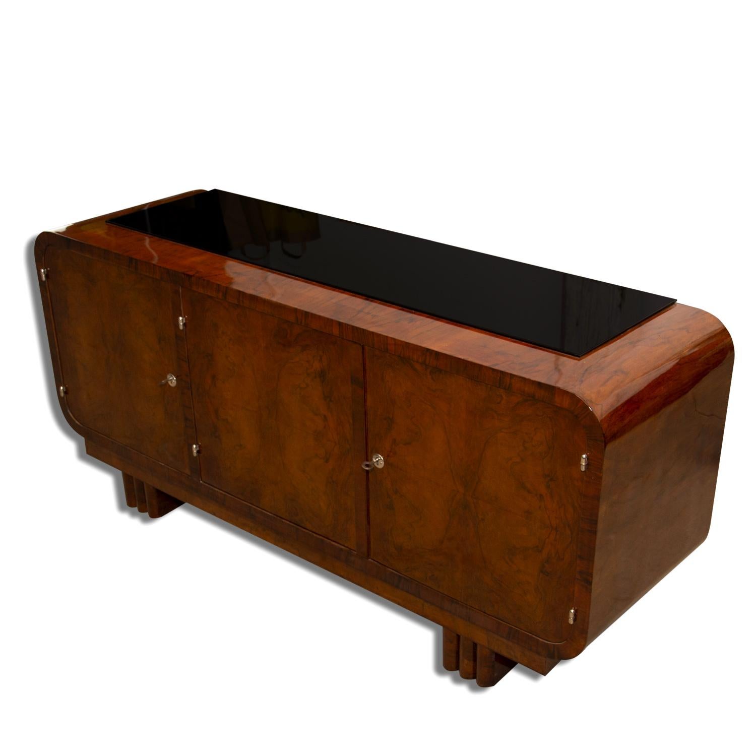 This sideboard or commode from the 1930s was made in Bohemia. It´s an example of Central European functionalism and is made of solid wood and veneered in walnut. It features a storage space divided to two parts and the top is covered with black