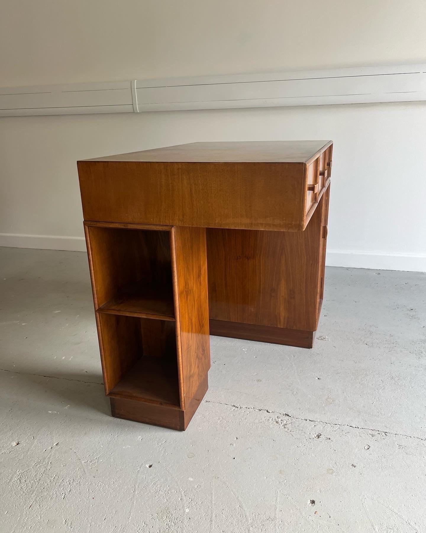Art Deco walnut desk in fabulous condition.

A beautiful piece perfect for a smaller study area.  Three draws, and a bookshelf on the left side of the leg.  Burr Walnut front and top.  

Dimensions are D:56cm x W: 88cm x H: 76cm x Under Desk Height