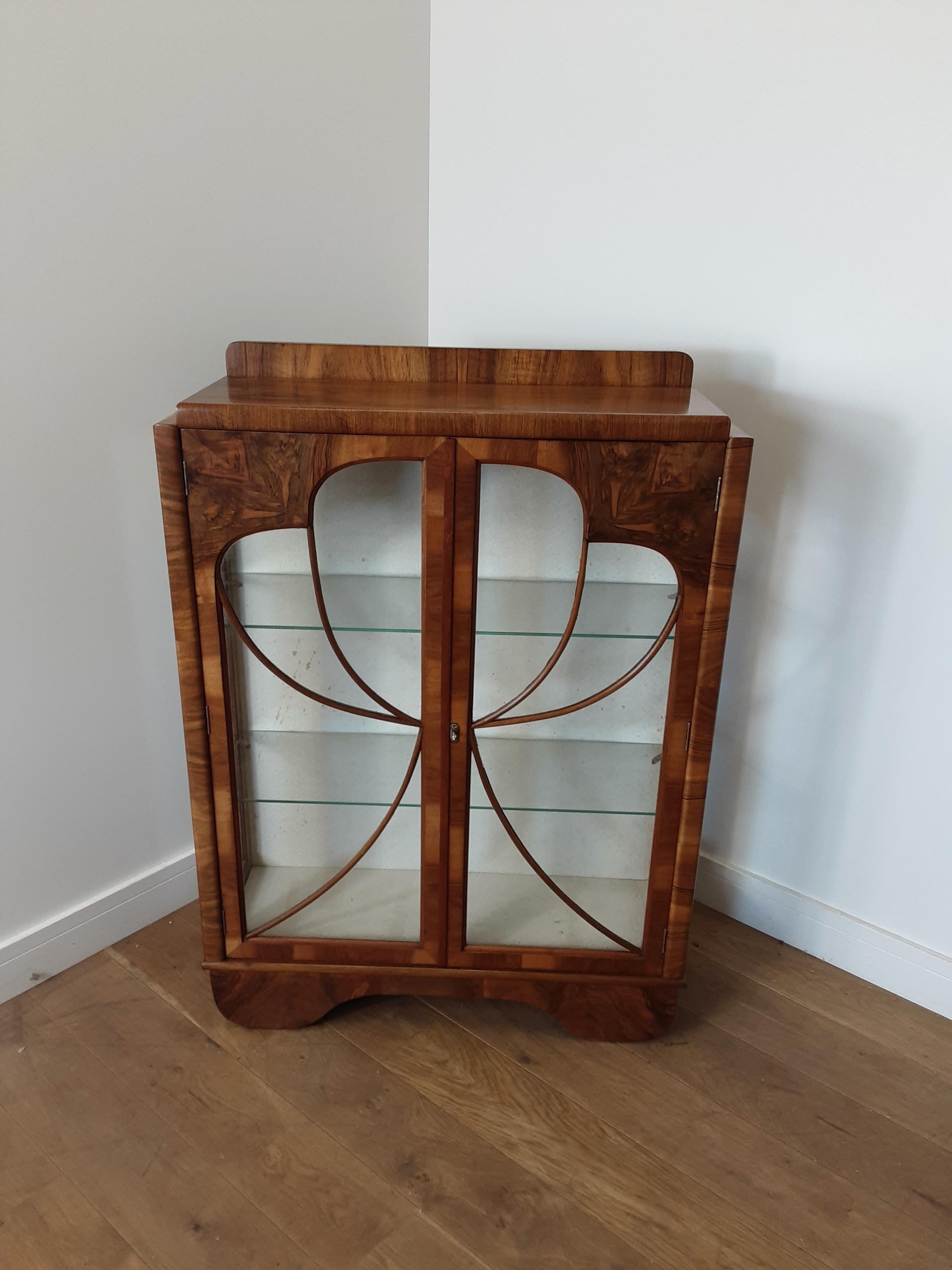 Art Deco vitrine in walnut with glazed front doors having a fretwork design of a butterfly. Also with glazed side panels giving plenty of light.
A very pretty display cabinet bookcase.
Measures: 122 cm H at the front 116 cm H at the back. 88 cm W,