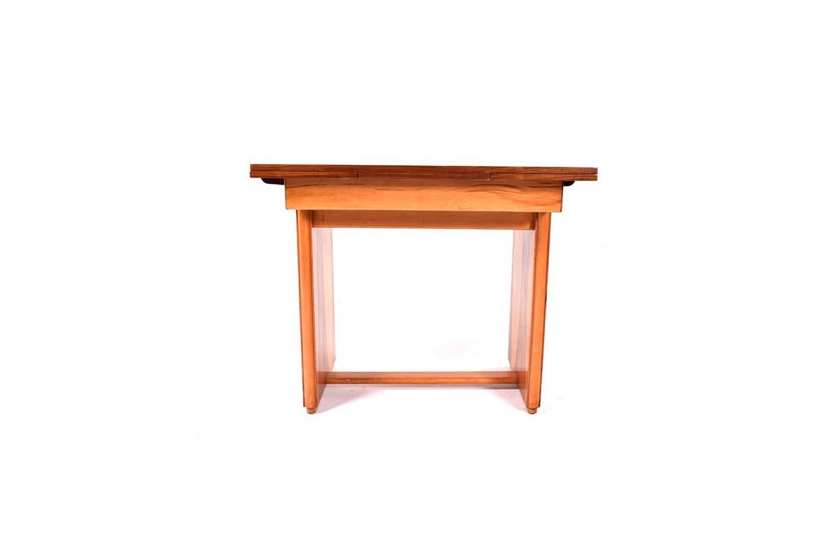 This is a beautifully crafted blond walnut extending dining table from the 1930s. It features two pull-out leaves, each extending the table by 27 cm, making it both practical and elegant for various dining needs. The table has a simple yet geometric