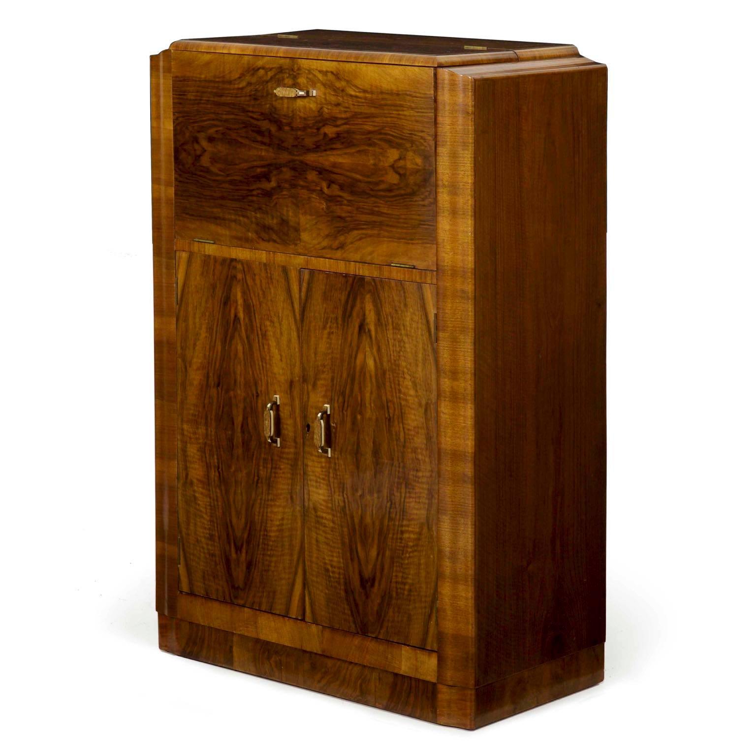 This is such an incredibly fine piece! In every sense true to the spirit of the Art Deco movement, this angular mini bar cabinet is simple in form while rich in material and design. The primary surfaces are all veneered in a dramatic walnut, the