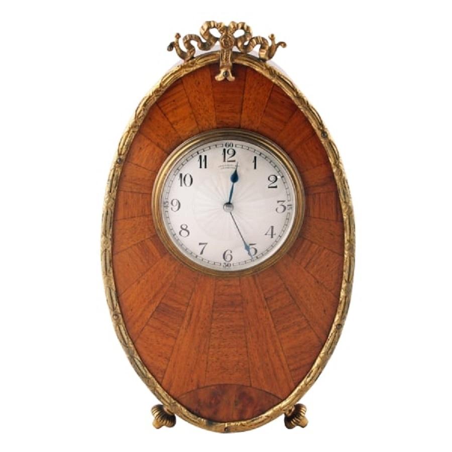 An early 20th century Art Deco design walnut mantel clock.

The clock has a gold coloured dial and bezel with black numerals and a French eight day movement works that winds and adjust from the back of the clock.

The oval case is made from a