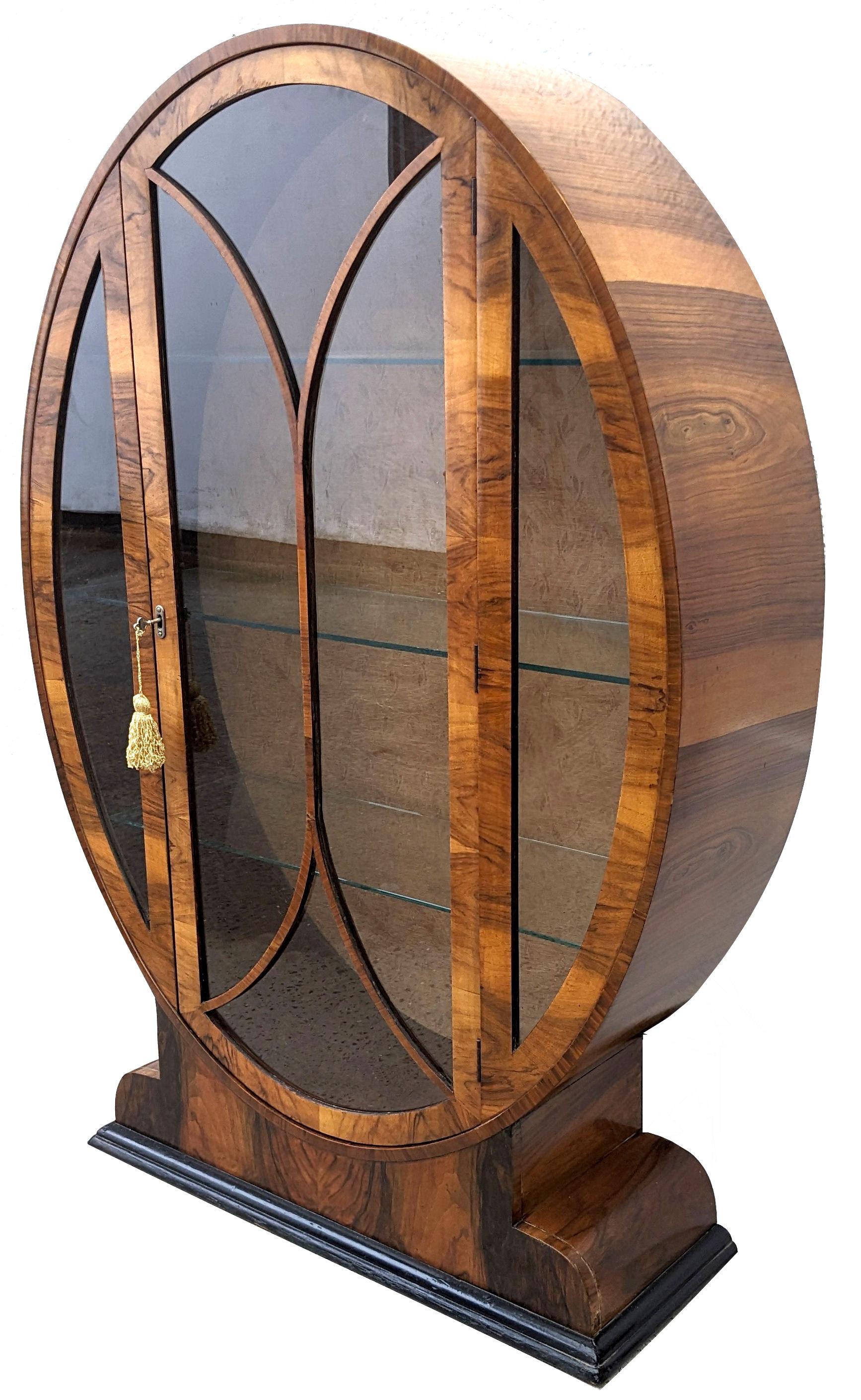 Very rare example of what is considered one of the more rare Art Deco display cabinets is this oval shaped heavily figured walnut veneered example. Fabulous piece of furniture, it truly is. Original silk lining as backing, shows some signs of age
