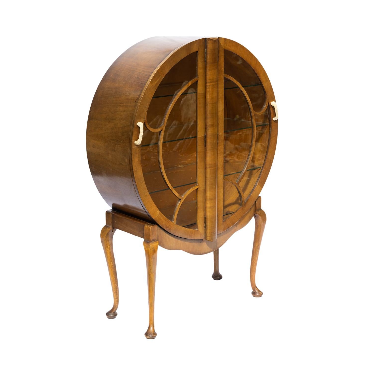 Art Deco Round Display Cabinet in Figured Walnut, with astregal glazed butterfly doors, with Bakalite handles, on Queen Anne cabriole legs, with glass shelves to the interior, the interior glazing bar with maker's badge, 'S. Spaglett, LTD, London,'