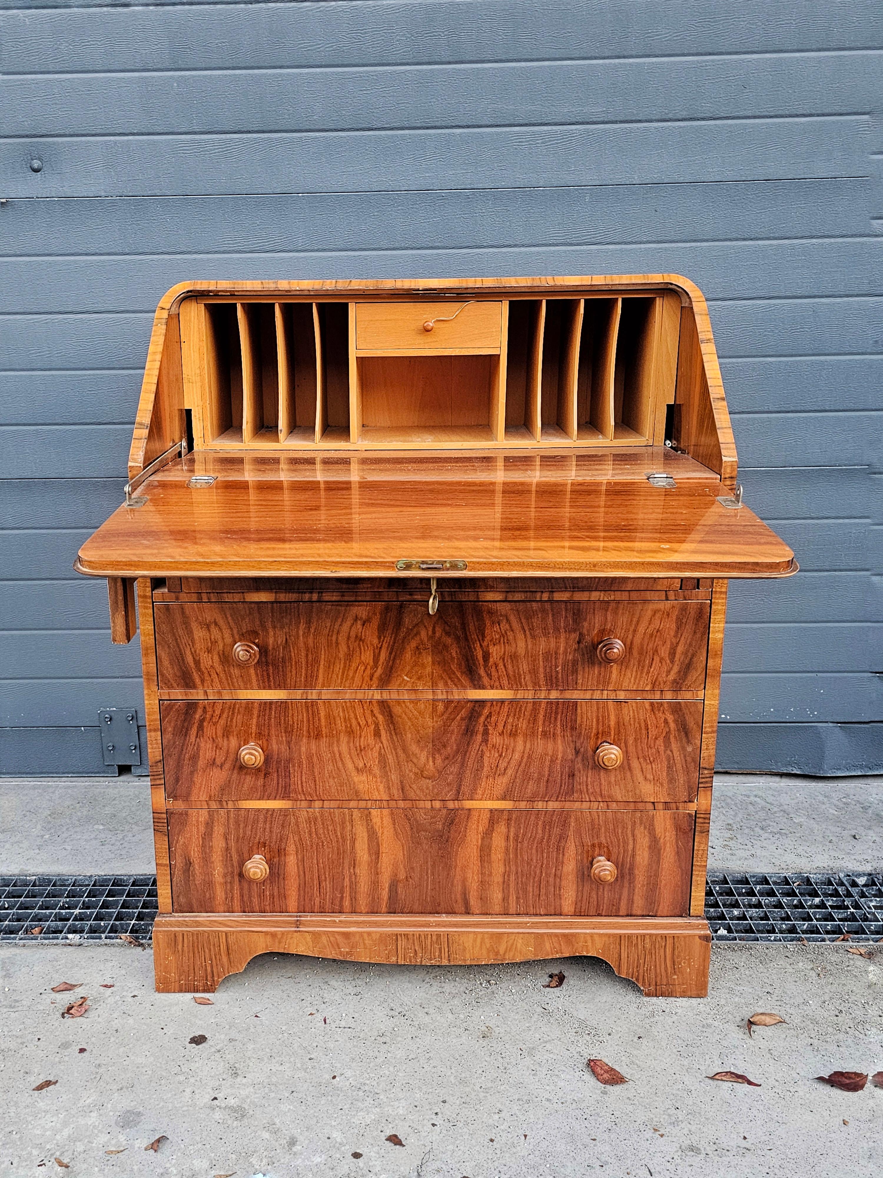 In questa inserzione troverai un sorprendente secretaire o bureau in noce Art Déco. Come puoi vedere, il bureau ha una raffinata finitura al pianoforte che mostra il meglio delle venature del noce. Il piano è impiallacciato a metà con fantastici