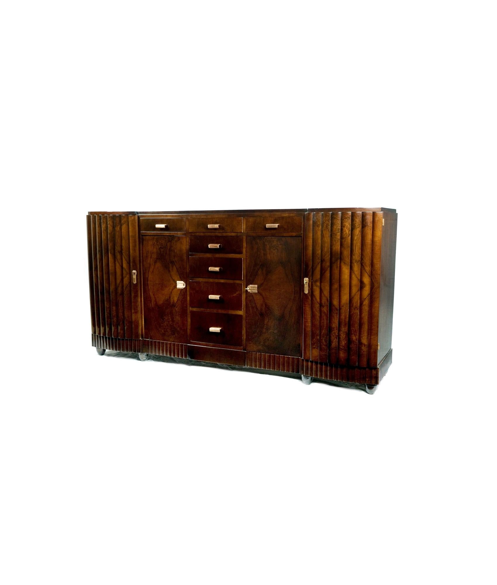 Questa grande credenza Art Déco del XX secolo ha un'ampiezza di ben 80 pollici (203,5 cm) in stile buffet e una ferramenta in ottone placcato che offre un supporto perfetto per la zona pranzo o la zona riposo, mantenendo linee simmetriche e pulite.