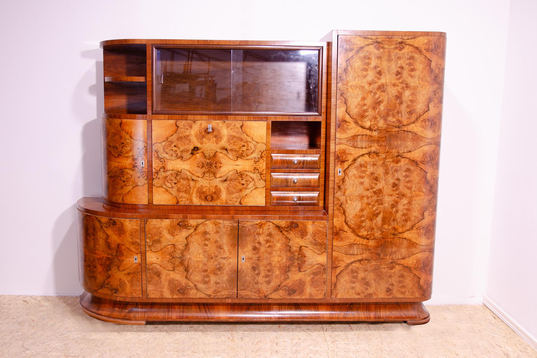 This huge ART DECO bookcase or sideboard was made in the 1930s in the former Czechoslovakia.
The bookcase has a beautiful rounded shapes, several storage spaces, including a glass section for books, etc. It also includes a bar section.
It is made of