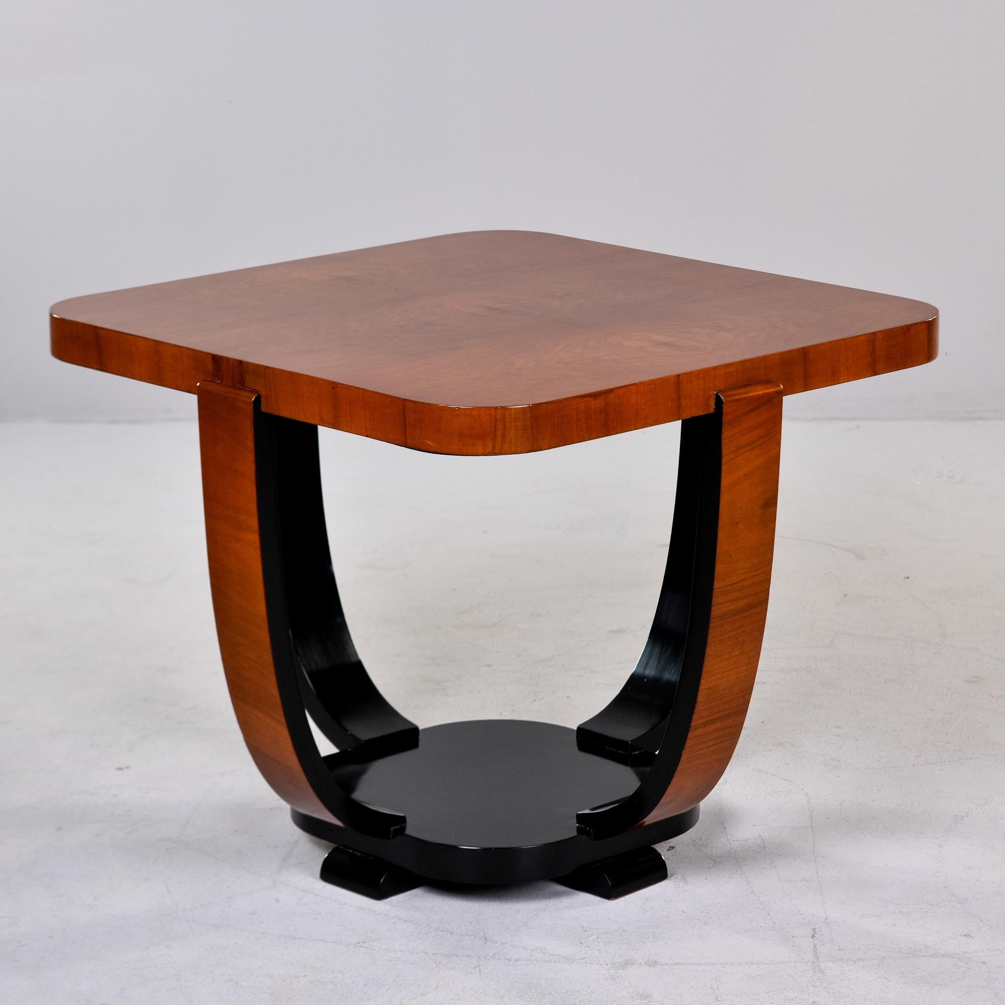 Found in France, this Art Deco side table dates from the 1930s. Square table top with rounded corners, four curved legs that connect to a round, footed base. Contrasting black finish on base and back sides of legs highlights the curves. Unknown
