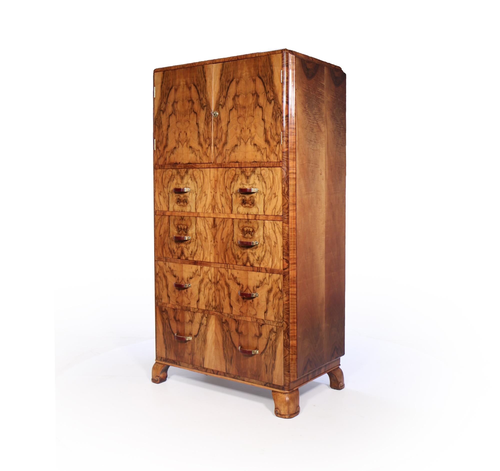A four drawer tall boy cabinet with lockable double doors on top, brass and red phenolic handles al standing unusual type of feet, the cabinet has been restored where necessary and fully polished by hand and is in excellent condition