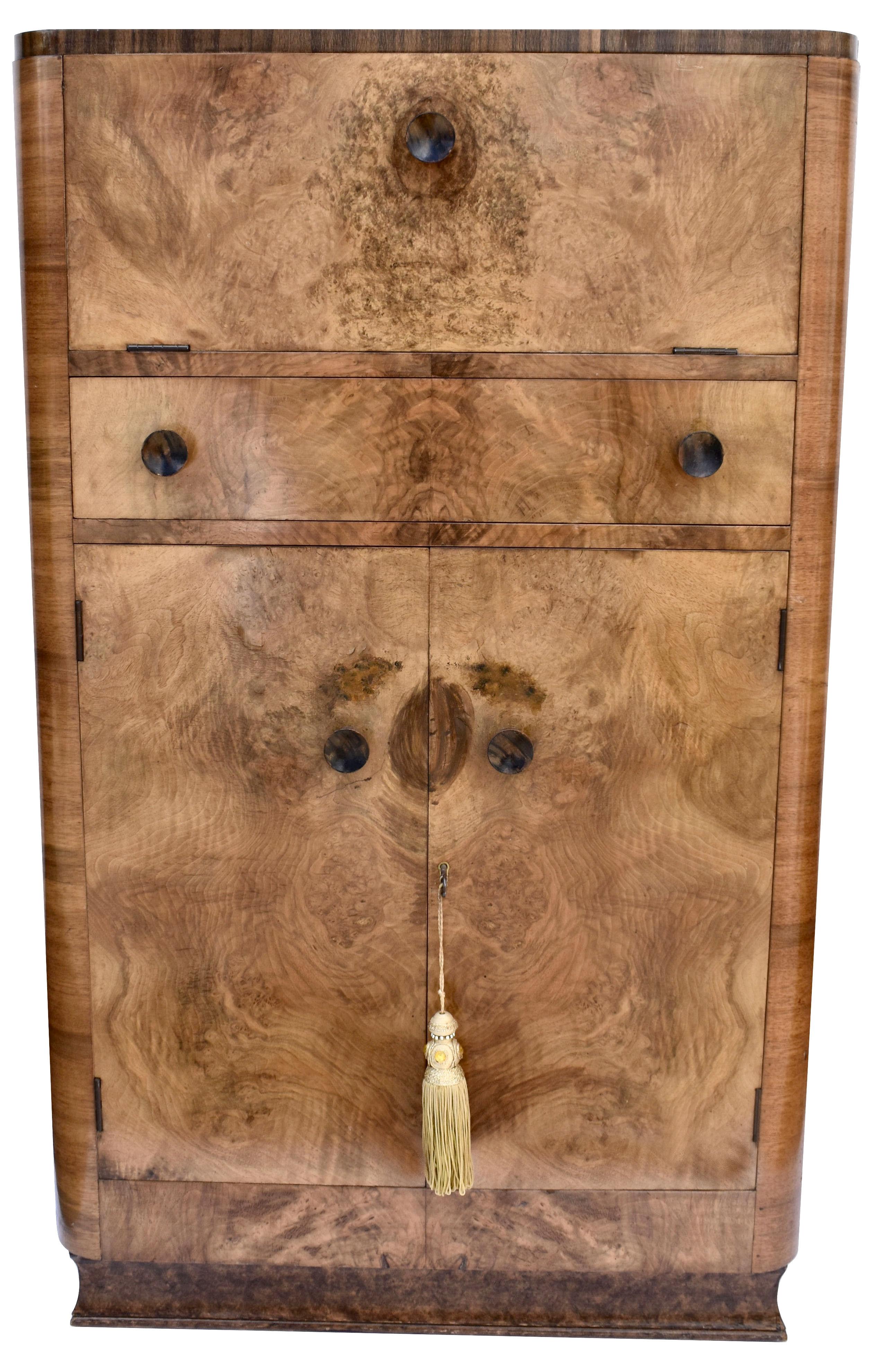 Beautiful 1930's Art Deco walnut upright cocktail cabinet, every Deco interior should have one of these ! Features a drop down top which reveals a mirrored interior and storage glasses. A generously sized cupboard below offers plenty of storage for