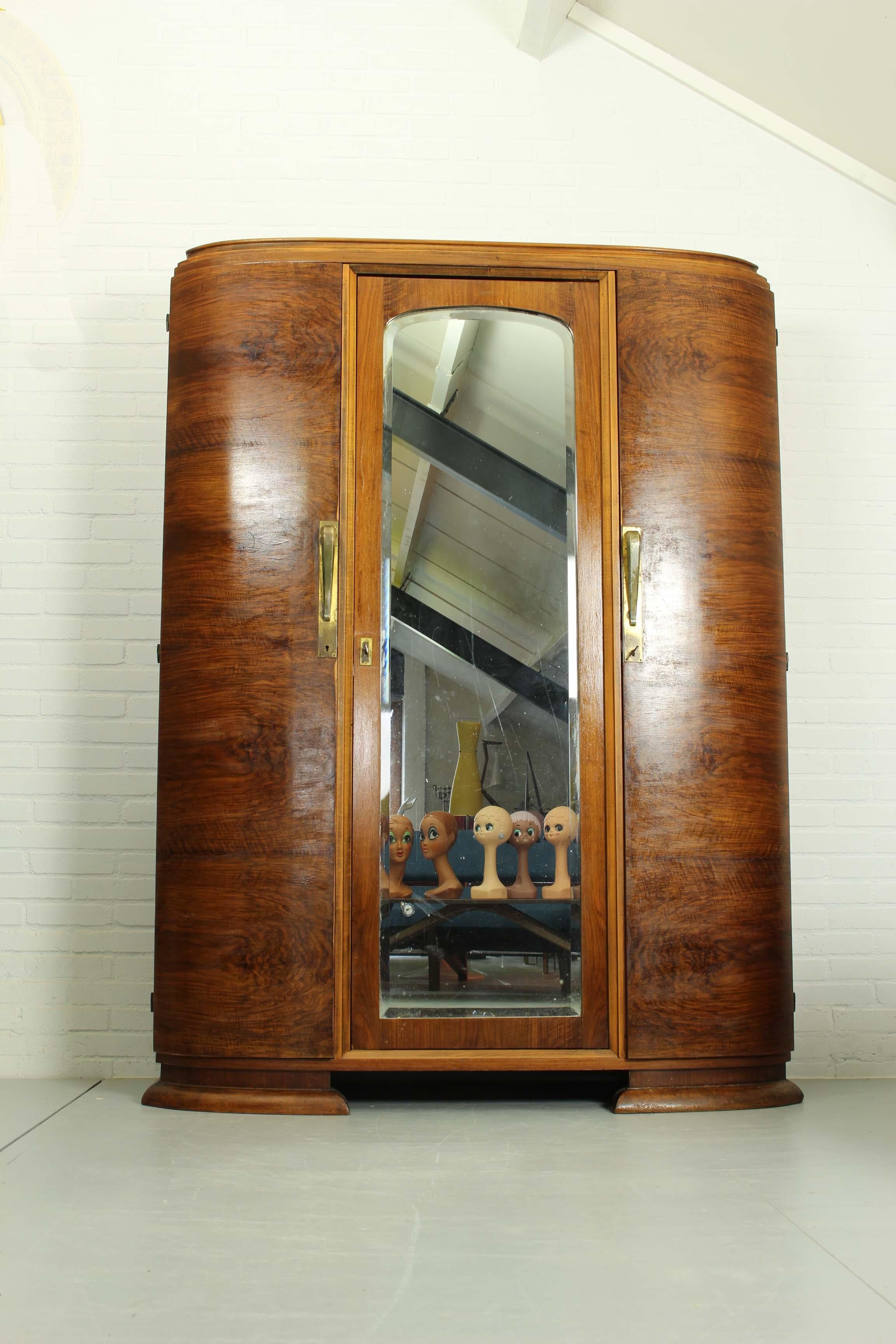 Une armoire Art Déco en noyer de grande qualité, produite par Georges Guerin à Paris dans les années 1920. 3 portes façonnées en noyer avec de belles poignées à l'extérieur et un tiroir derrière. Miroir à bord biseauté sur la porte du milieu. En bon