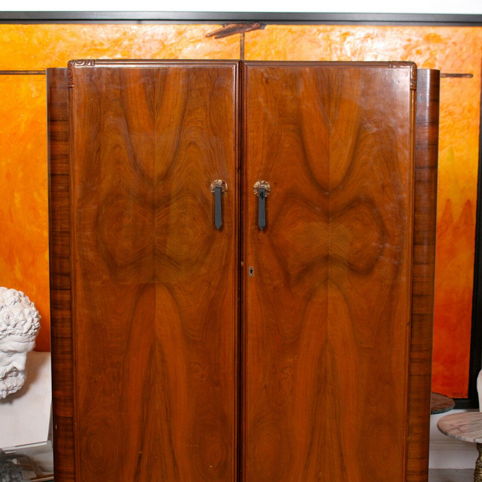 An impressive Art Deco walnut wardrobe.

The doors with inlaid marquetry panels, mounted with good ebonized handles, flanked by rounded marquetry sides and plinth base and enclosed a camphor lined interior with shelving, mirror and two hanging