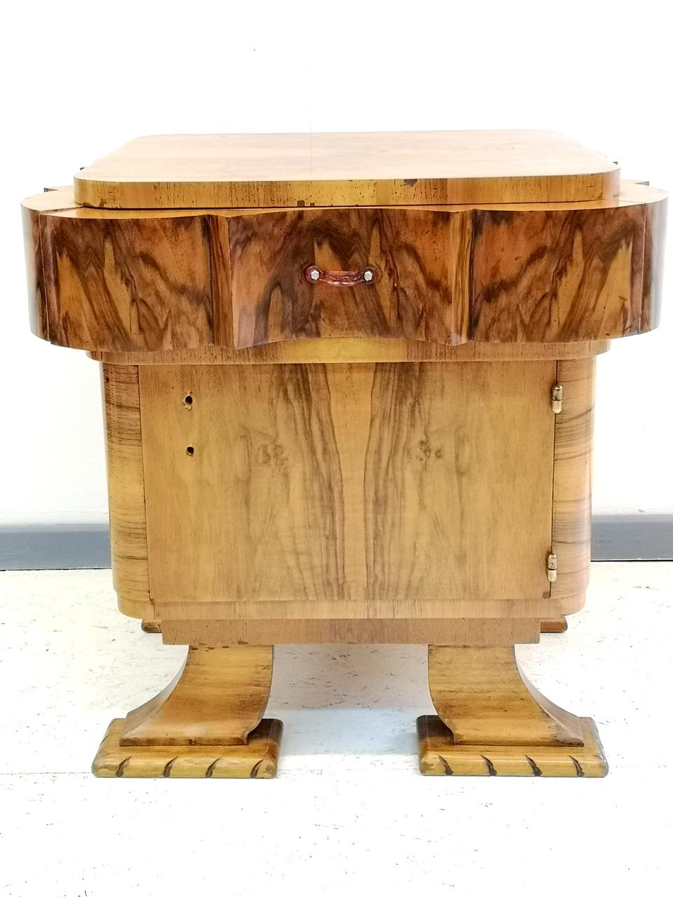This stylish Art Deco piece features walnut wood veneer- French polished with shellac. It has one drawer and one door storage with a shelf. It has it's original bakelite handle, unfortunately one is missing. Generally it's in good condition, as