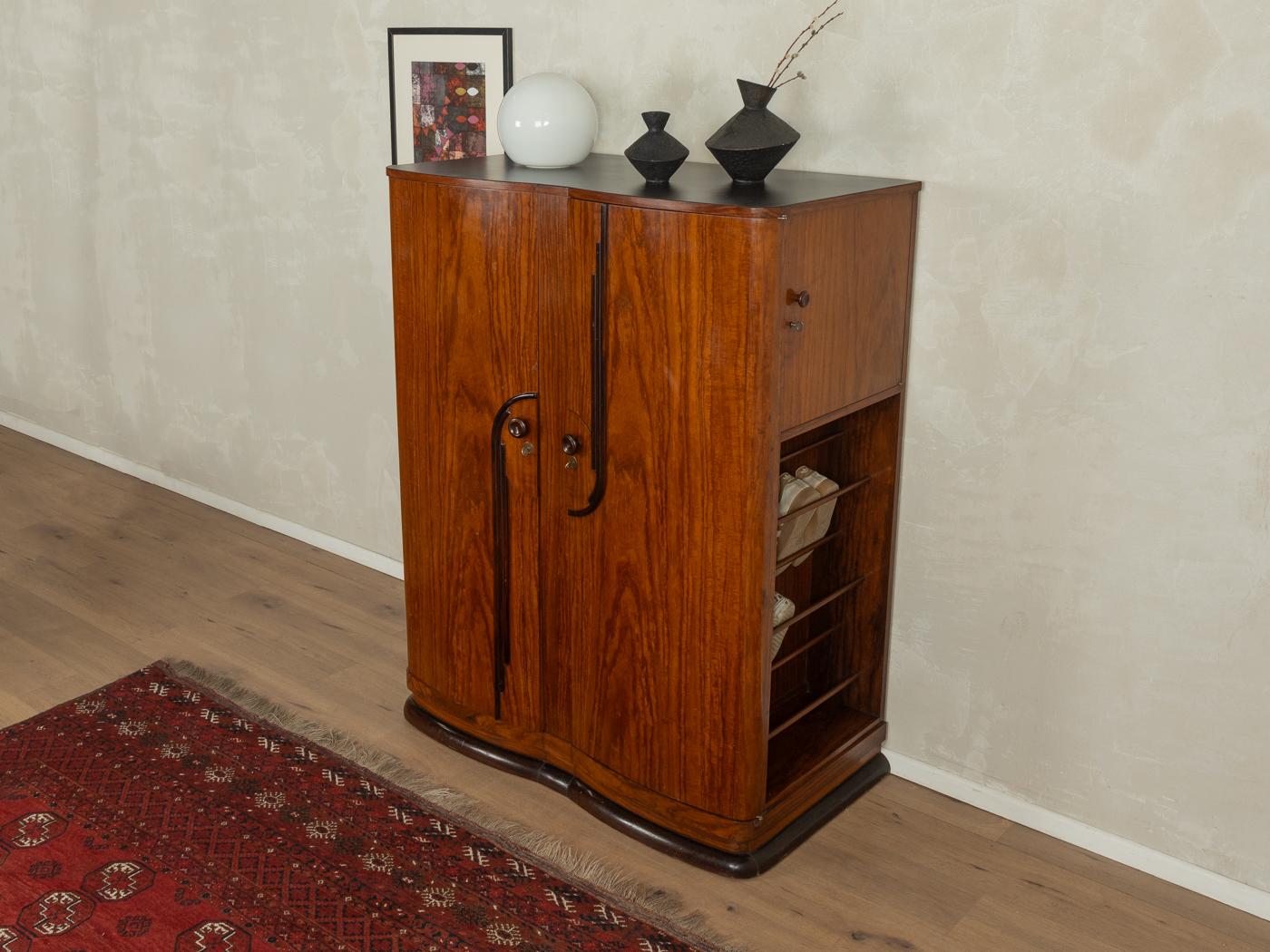 Maravilloso armario Art Déco de los años veinte. Corpus de teca maciza de alta calidad con tres puertas, cuatro estantes, dos cajones interiores, zapatero y una base típica. La parte superior y un lateral están recubiertos de fórmica