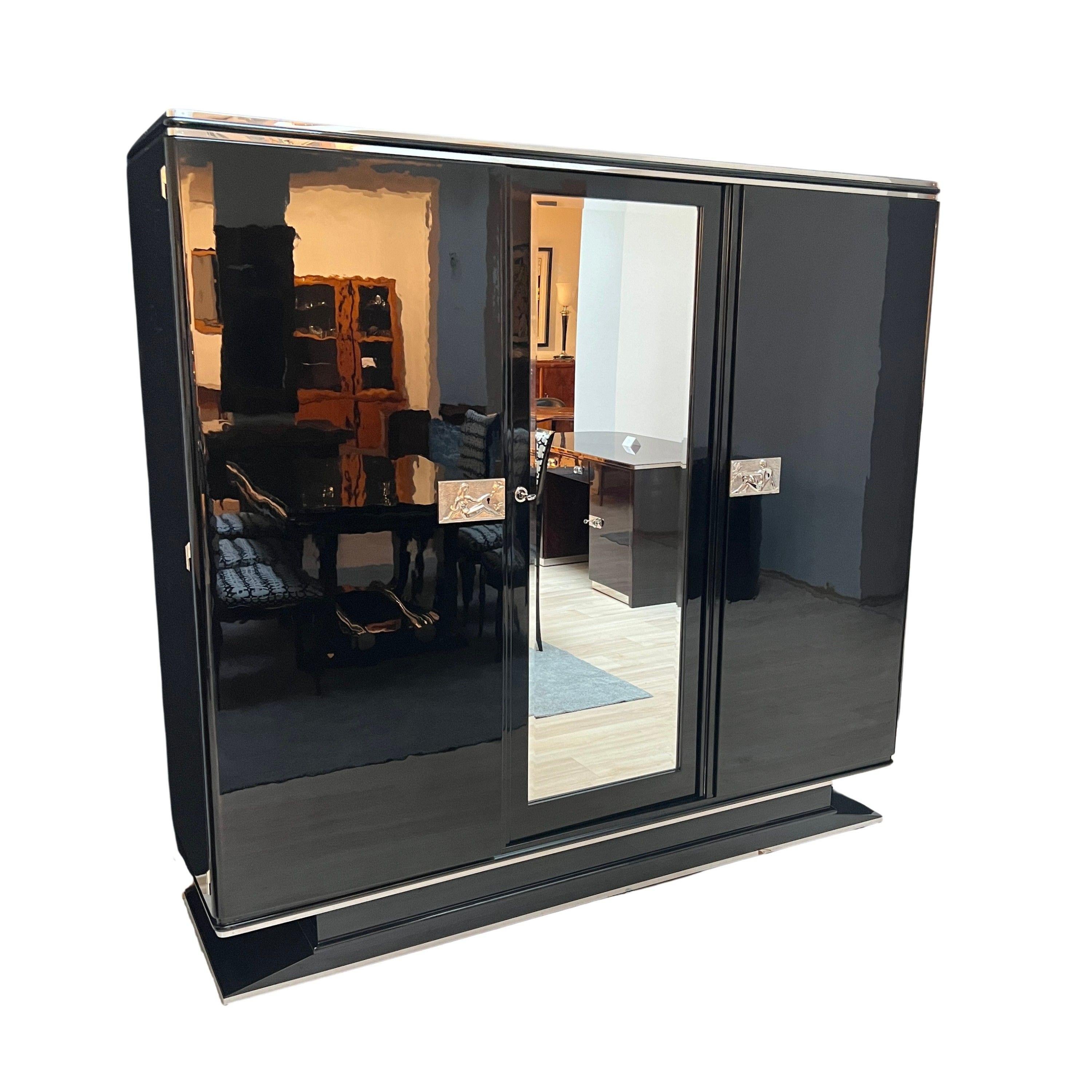 Outstanding Art Deco Armoire or Wardrobe in black piano lacquer from France around 1930.
Mahogany body, outside in black piano lacquer, polished to high gloss. Double metal trim on the cornice and single trim on the base. A recessed mirror with