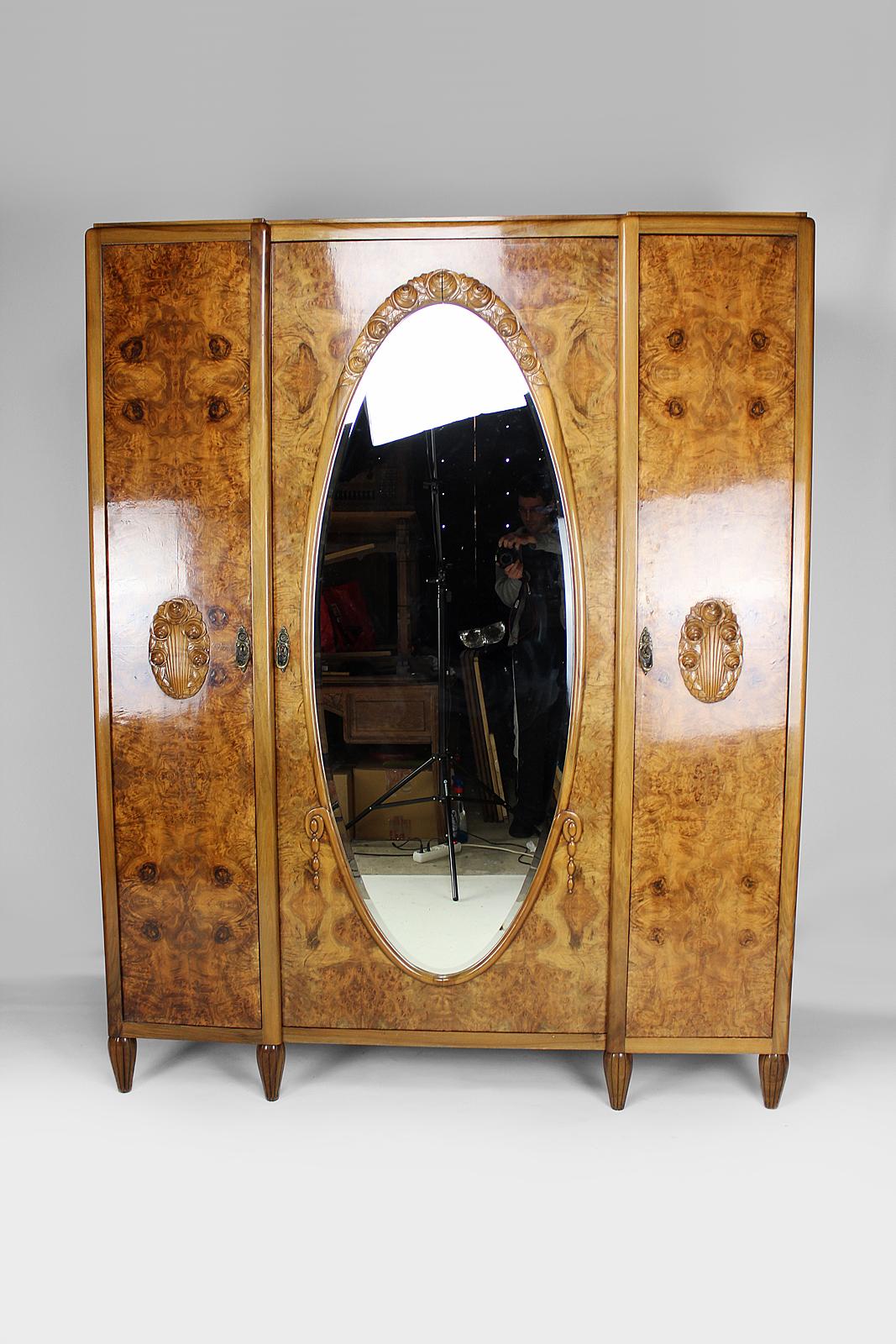 Superb Gauthier-Poinsignon wardrobe in burr walnut and walnut, composed of a large central door with a beveled oval mirror and 2 side doors.

Model with roses: we find them sculpted in a garland above the mirror, in bouquets on each side door, and