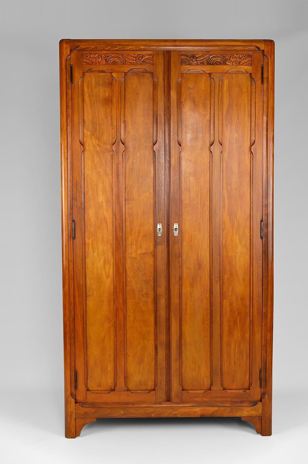 Elegant small cupboard / wardrobe / cabinet in beech wood. 

2 doors nicely carved with stylized flowers and fruits, typically Art Deco.
Chrome / nickel escutcheons.
Inside, a shelf and a clothes rack bar.

Art Deco style, France, circa 1930.

In
