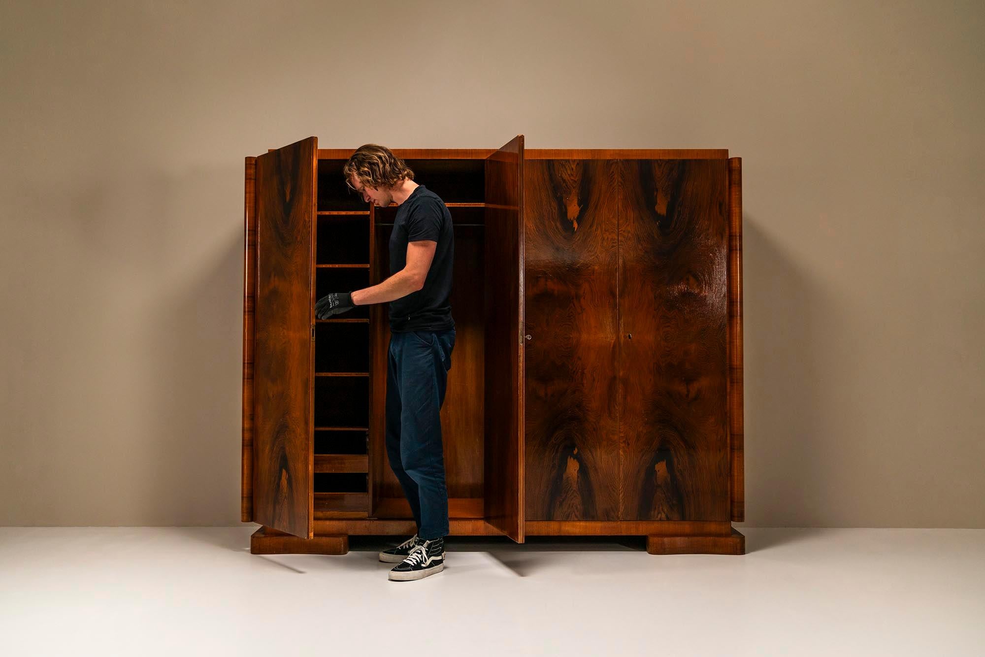 Art Deco wardrobe in rosewood by 't Woonhuys.It's impossible not to notice this wardrobe when you walk into the room. The bizarre drama that the palissander  veneer shows in combination with the imposing stature of the cabinet makes a crushing