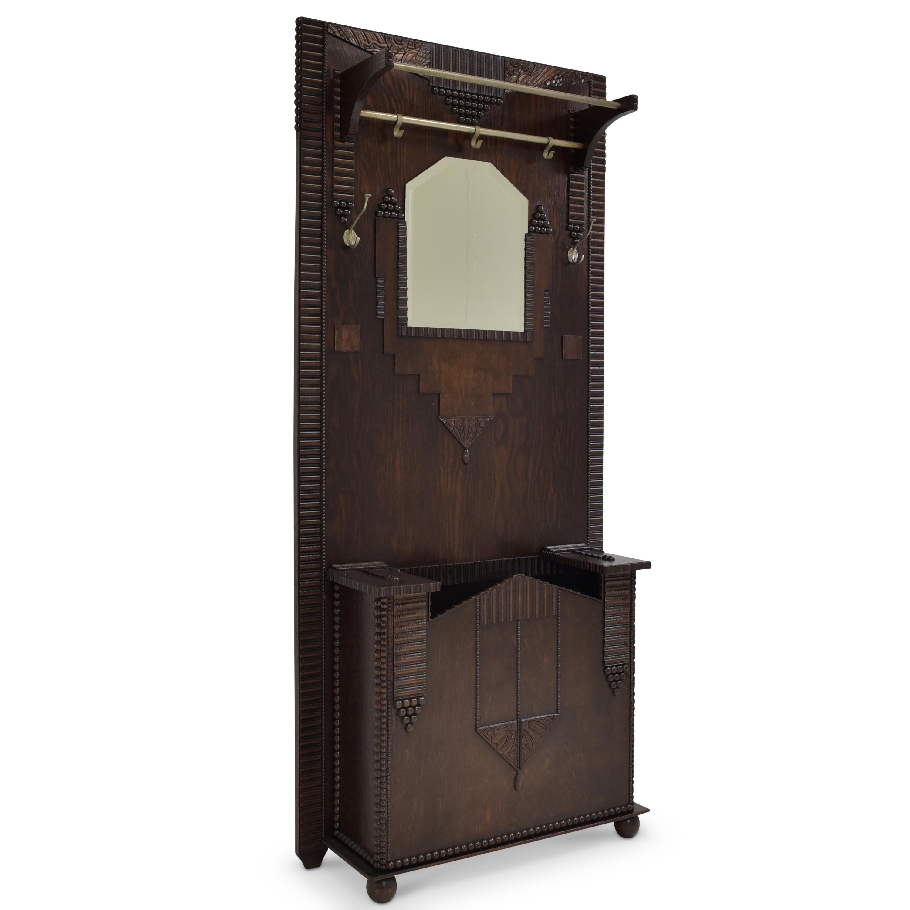 Wardrobe restored Art Deco around 1930 dark oak wall wardrobe

Features:
With rods, mirror, hook and large umbrella stand
Heavily decorated with geometric applications and abstract carvings
Original faceted mirror
Typical geometric Art Deco