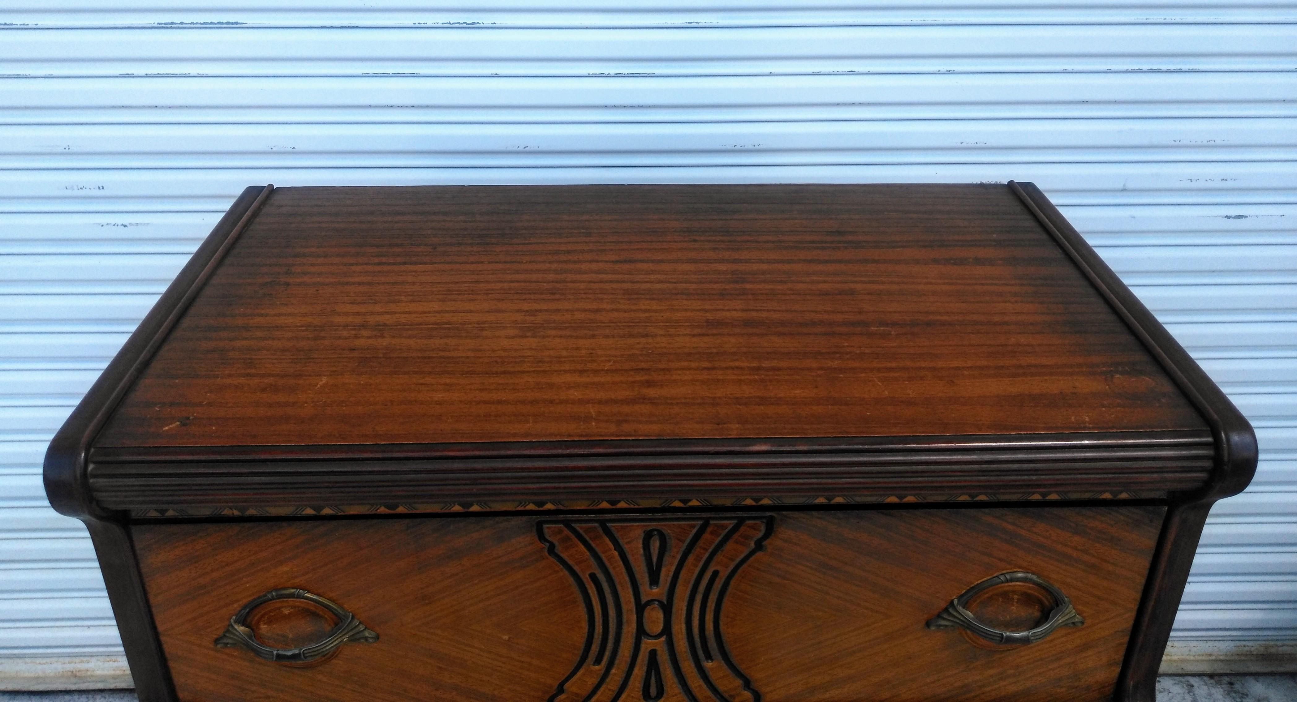 Si tratta di una favolosa cassettiera Art Déco. Ha i suoi tiranti originali in bachelite. È realizzato in noce e presenta intarsi e motivi intagliati. Dispone di 4 cassetti profondi per un ampio spazio di archiviazione. È dotato di rotelle per una