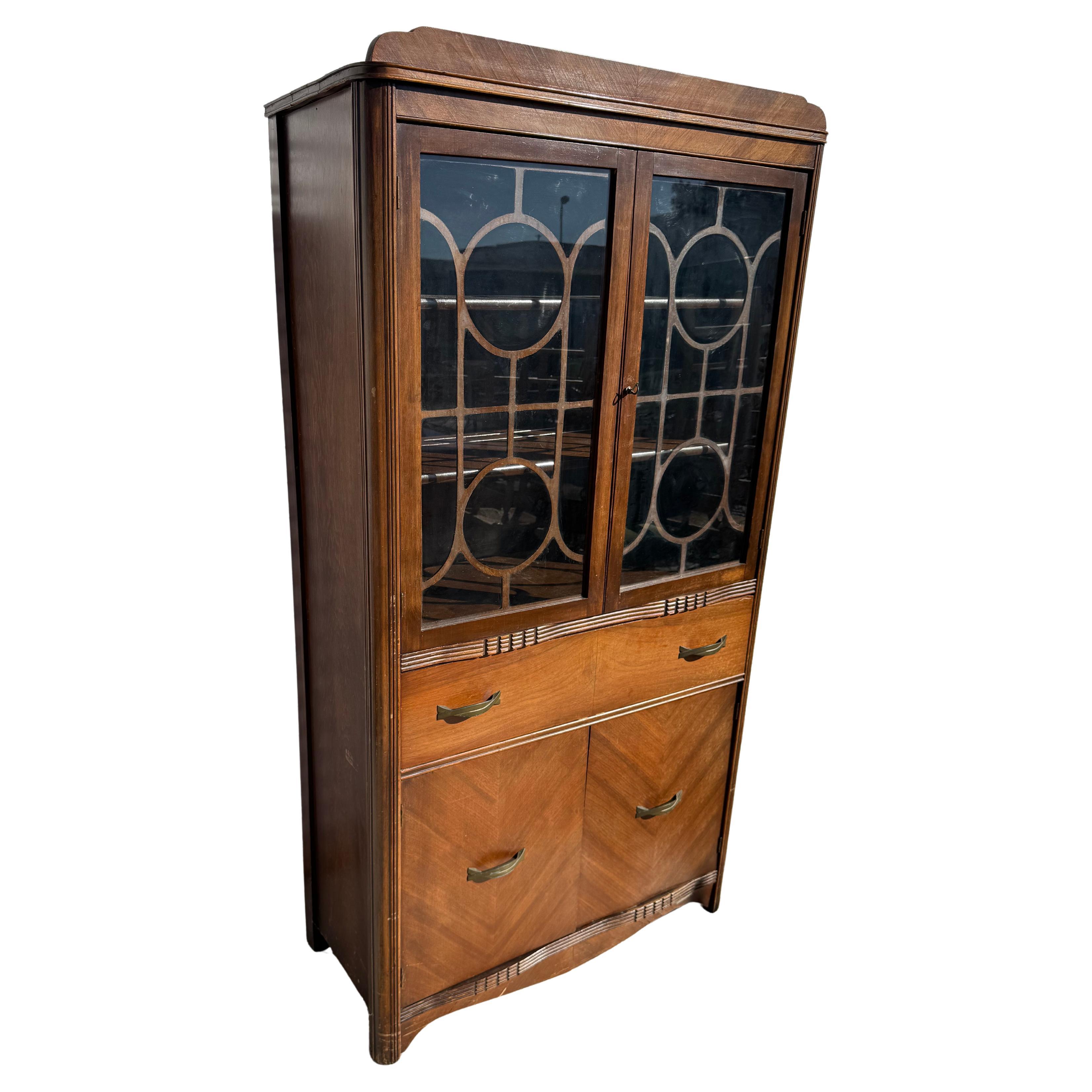 Cette armoire est en noyer.
Les vitres sont ornées d'une garniture en bois de style art déco.
Il comporte un tiroir unique et un meuble à deux portes dans la partie inférieure.
pour un grand espace de rangement supplémentaire. 