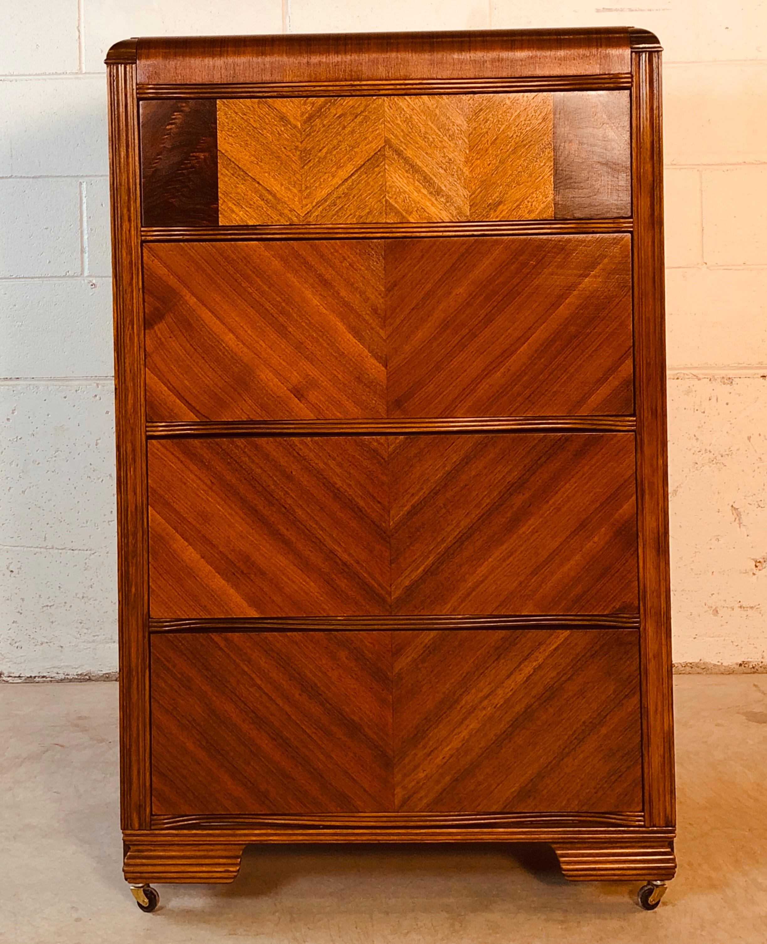 Vintage Art Deco waterfall style matchbook veneer tall four drawer dresser. The dresser has deep drawers for storage and is on castors. Newly refinished and in excellent condition. No marks.