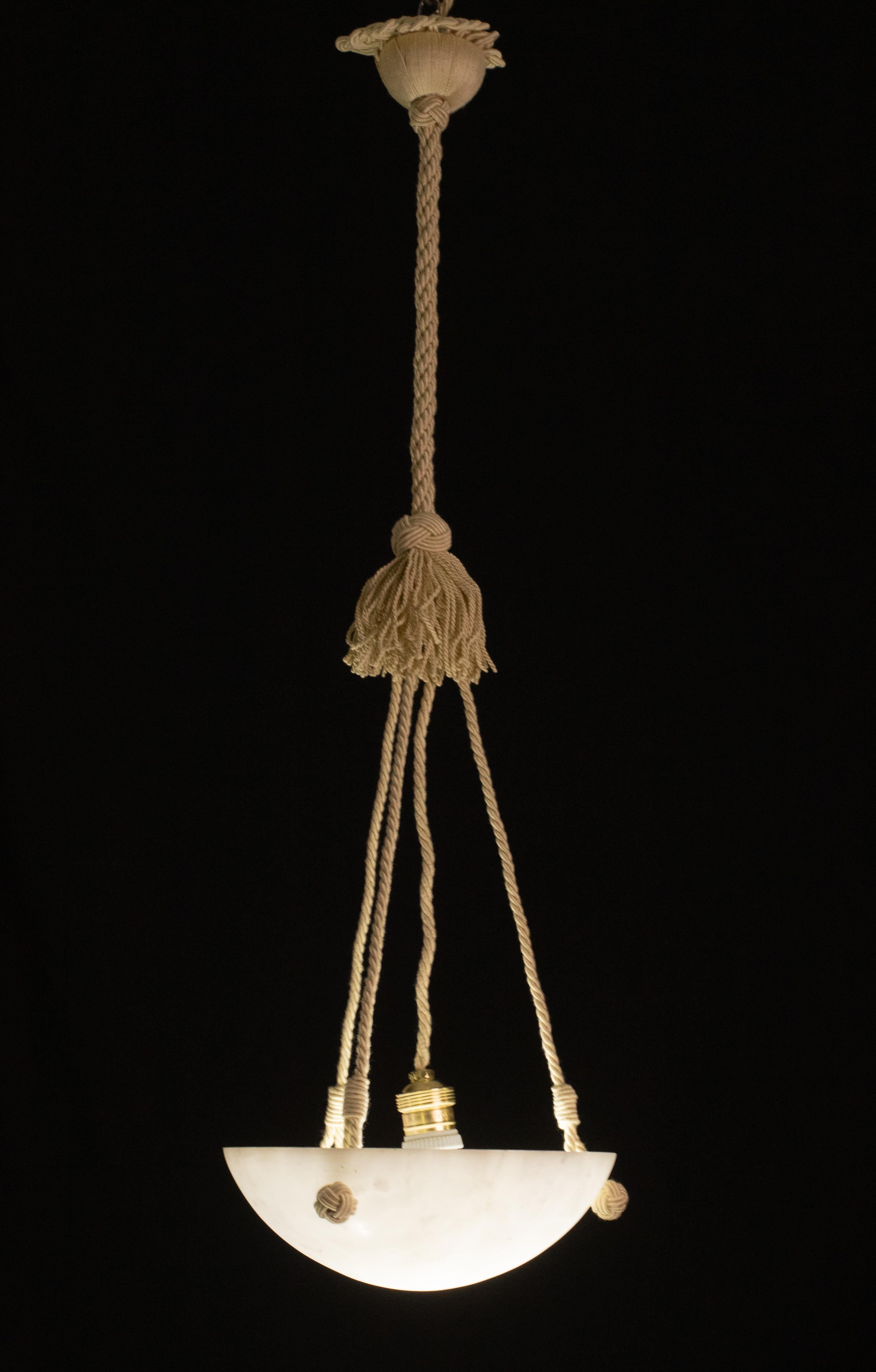 Antique alabaster hanging lamp in Art Deco style, circa 1950s. 
A single piece of alabaster, beautifully worked with hues and reflections of other colours when lit, suspended from three fabric ropes.
The stone is original vintage, perfect vintage